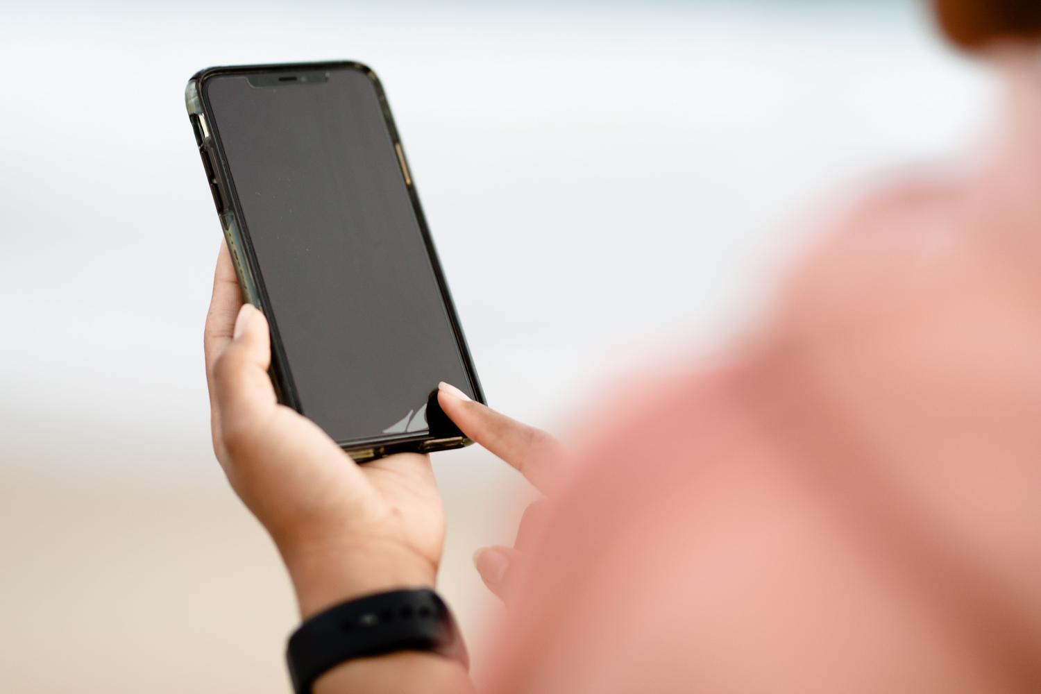 Primer plano de una mano interactuando con la pantalla de un smartphone moderno.