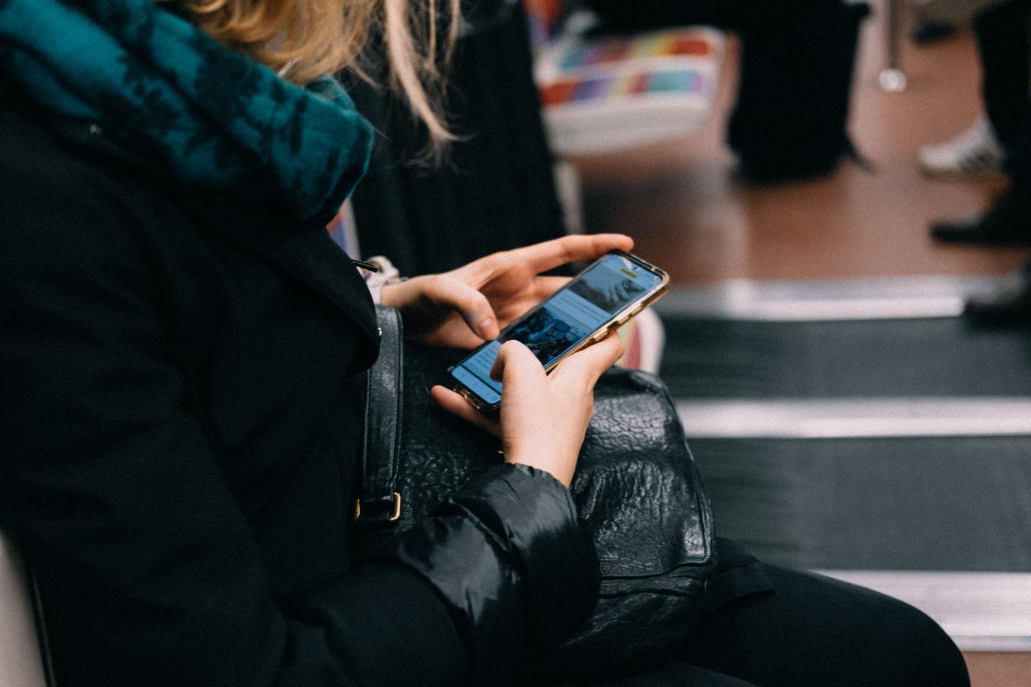 Persona utilizando el móvil durante un trayecto en transporte público, mostrando el contexto general de uso de dispositivos en movimiento.