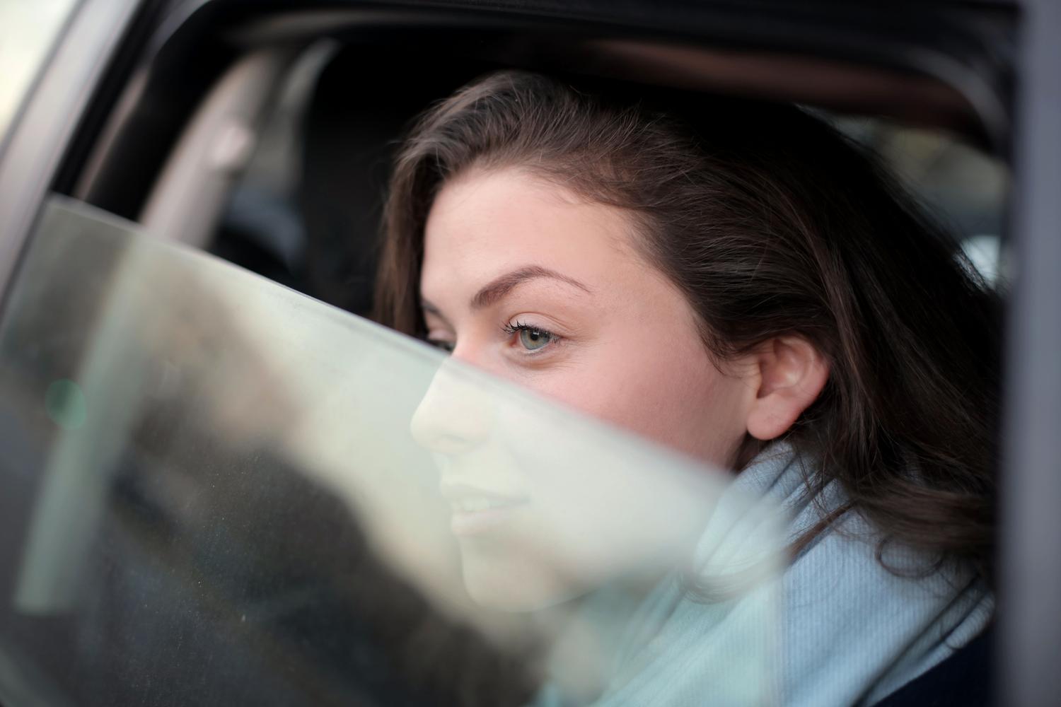 Mujer mirando pensativa a través de la ventana de un coche, representando la recomendación de enfocar objetos lejanos para reducir el malestar.