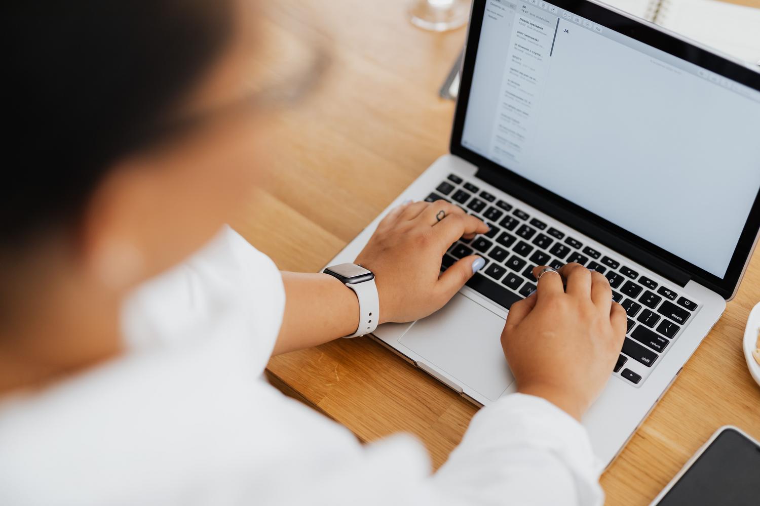 Primer plano de unas manos escribiendo en el teclado de un ordenador, representando la configuración de filtros y etiquetas en Gmail.