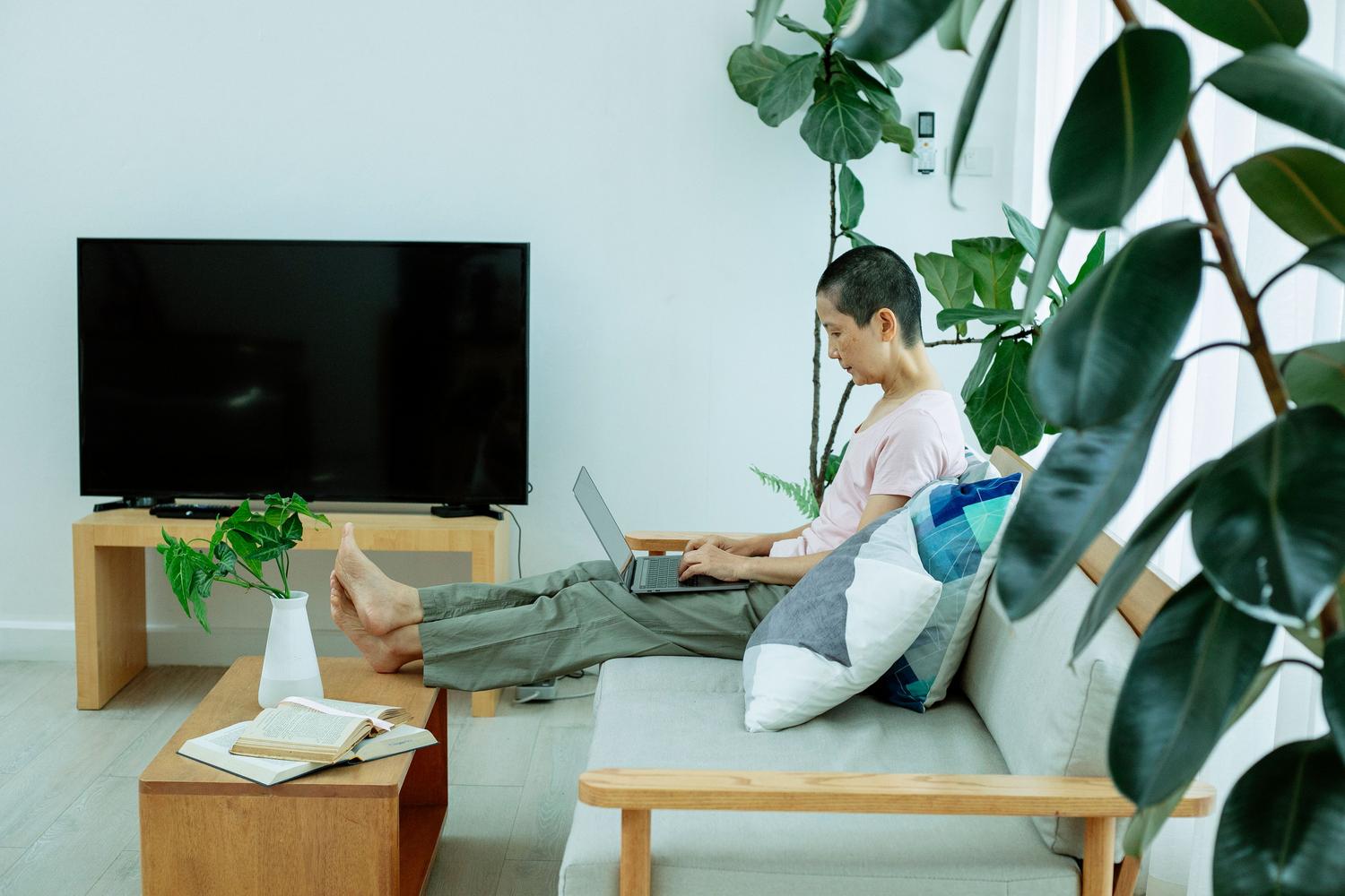 Persona utilizando un ordenador portátil en el sofá junto al televisor para configurar el modo desarrollador.