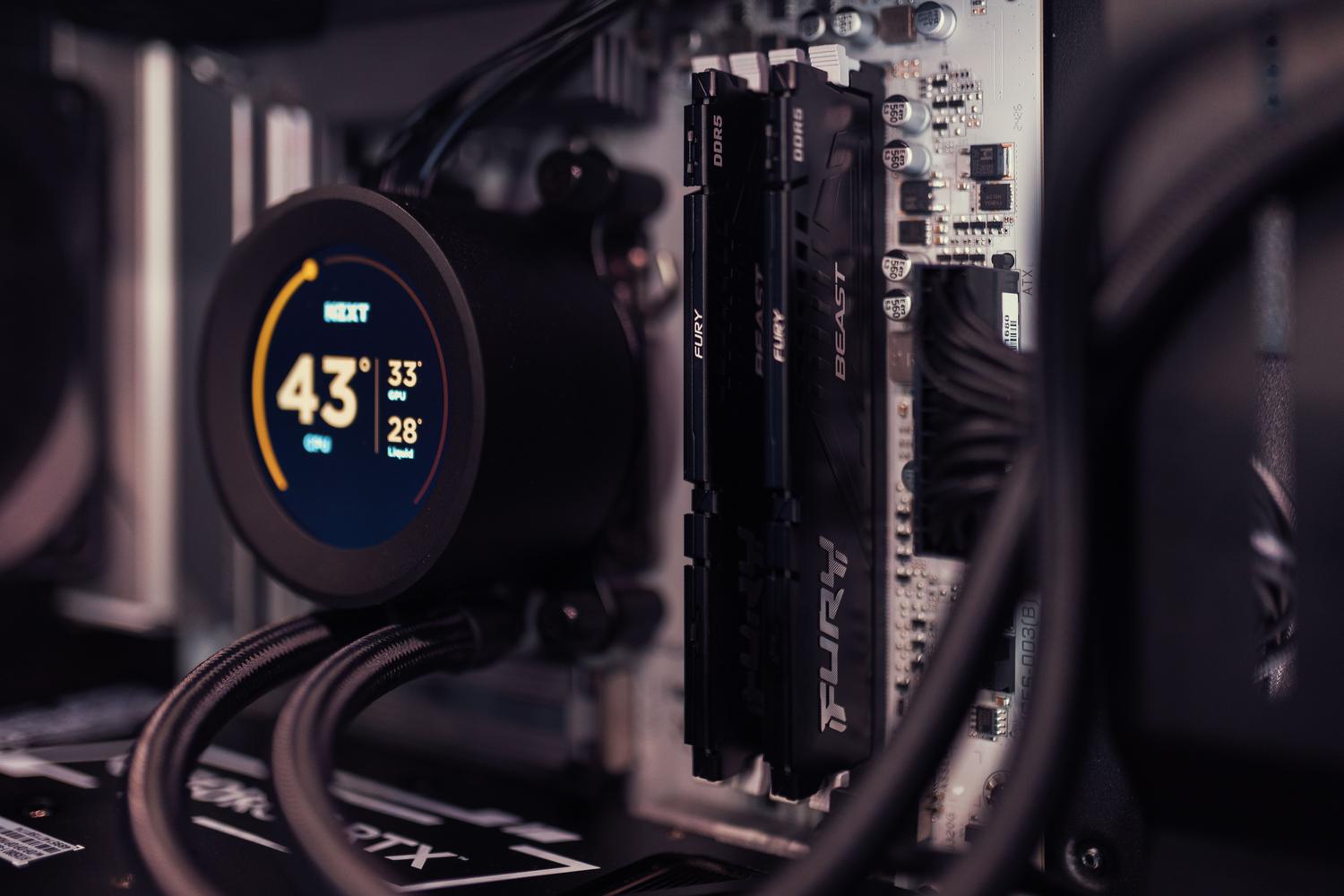 Primer plano del interior de un PC con una pantalla digital en la refrigeración mostrando la temperatura de la CPU y GPU, ilustrando la monitorización térmica.