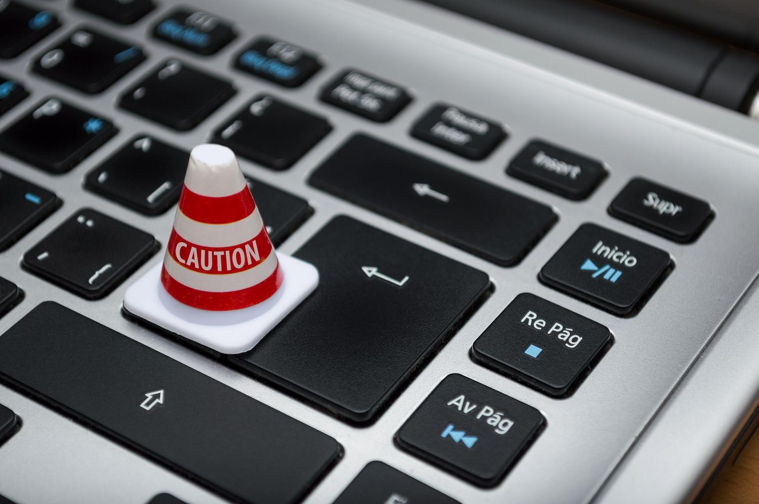 Miniatura di un cono di segnalazione su una tastiera di computer, a simboleggiare la necessità di fermarsi e verificare prima di interagire con un CAPTCHA.