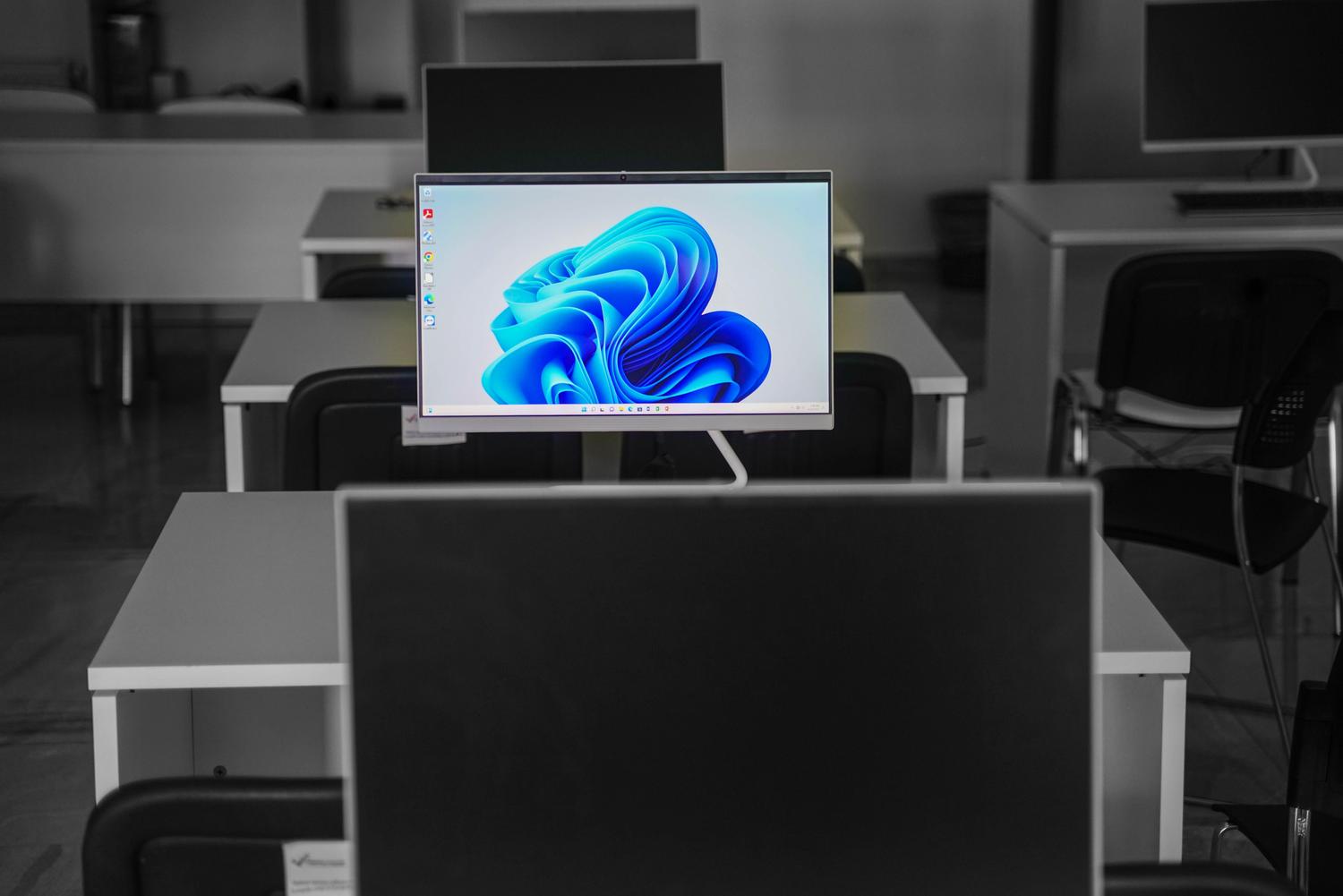 Oficina moderna con computadoras y monitores planos, ilustrando la migración hacia versiones actuales como Windows 11.