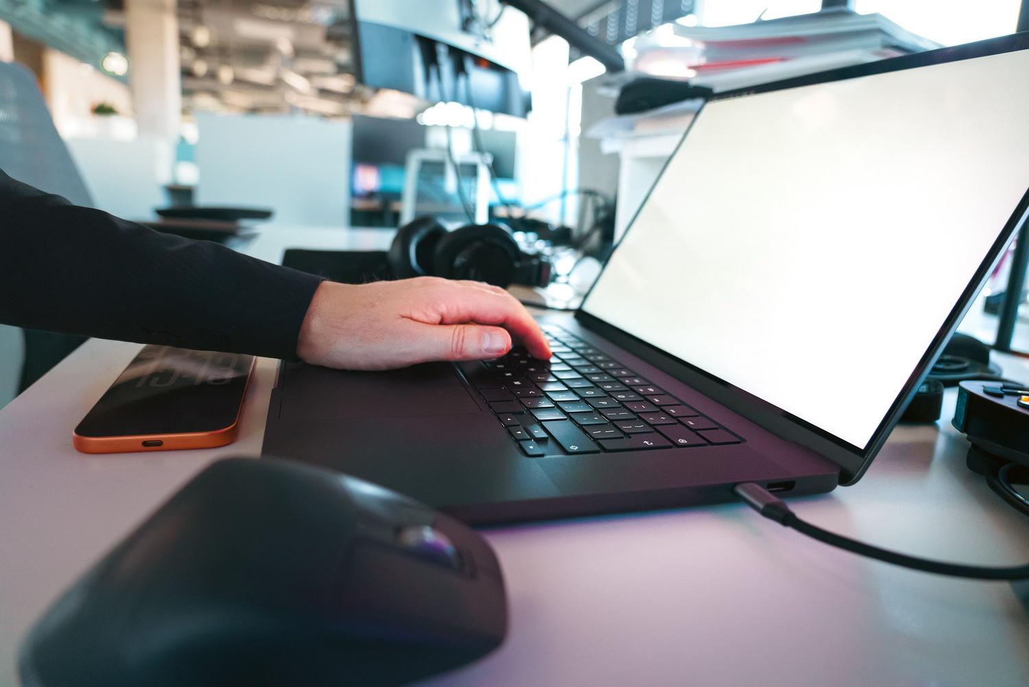 Közeli kép: kezek gépelnek egy laptop billentyűzetén irodai környezetben