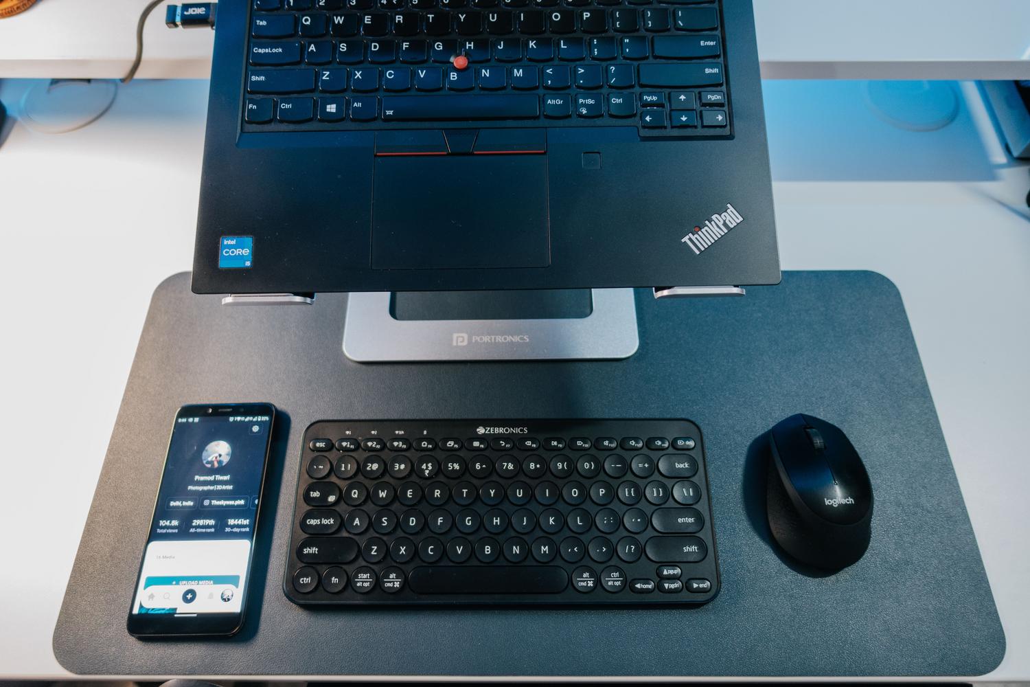 Espacio de trabajo moderno con portátil, teclado y ratón Bluetooth sobre un escritorio organizado.