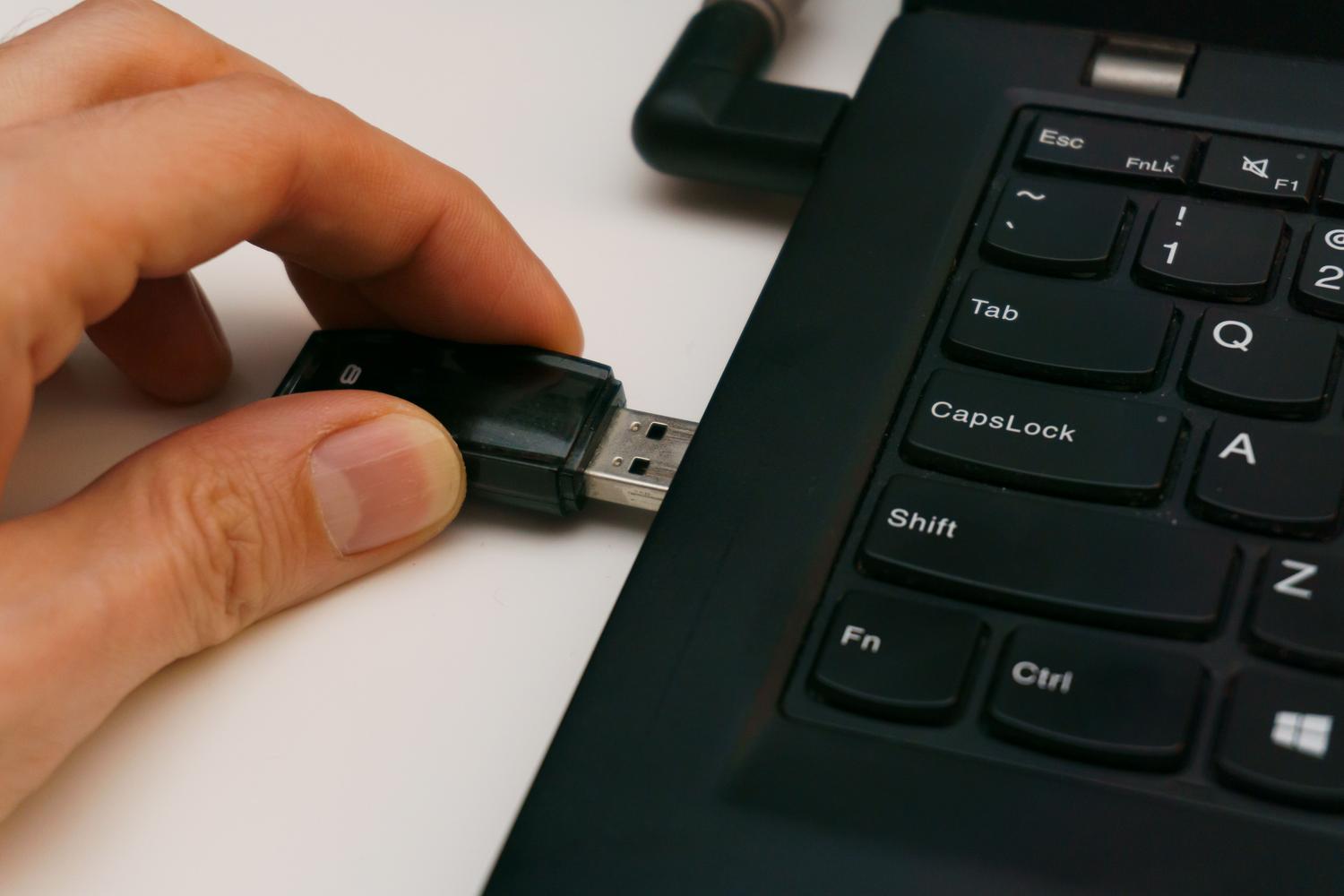 Primer plano de un dispositivo USB siendo conectado a un ordenador, ilustrando los métodos de transferencia manual o mediante software de terceros.