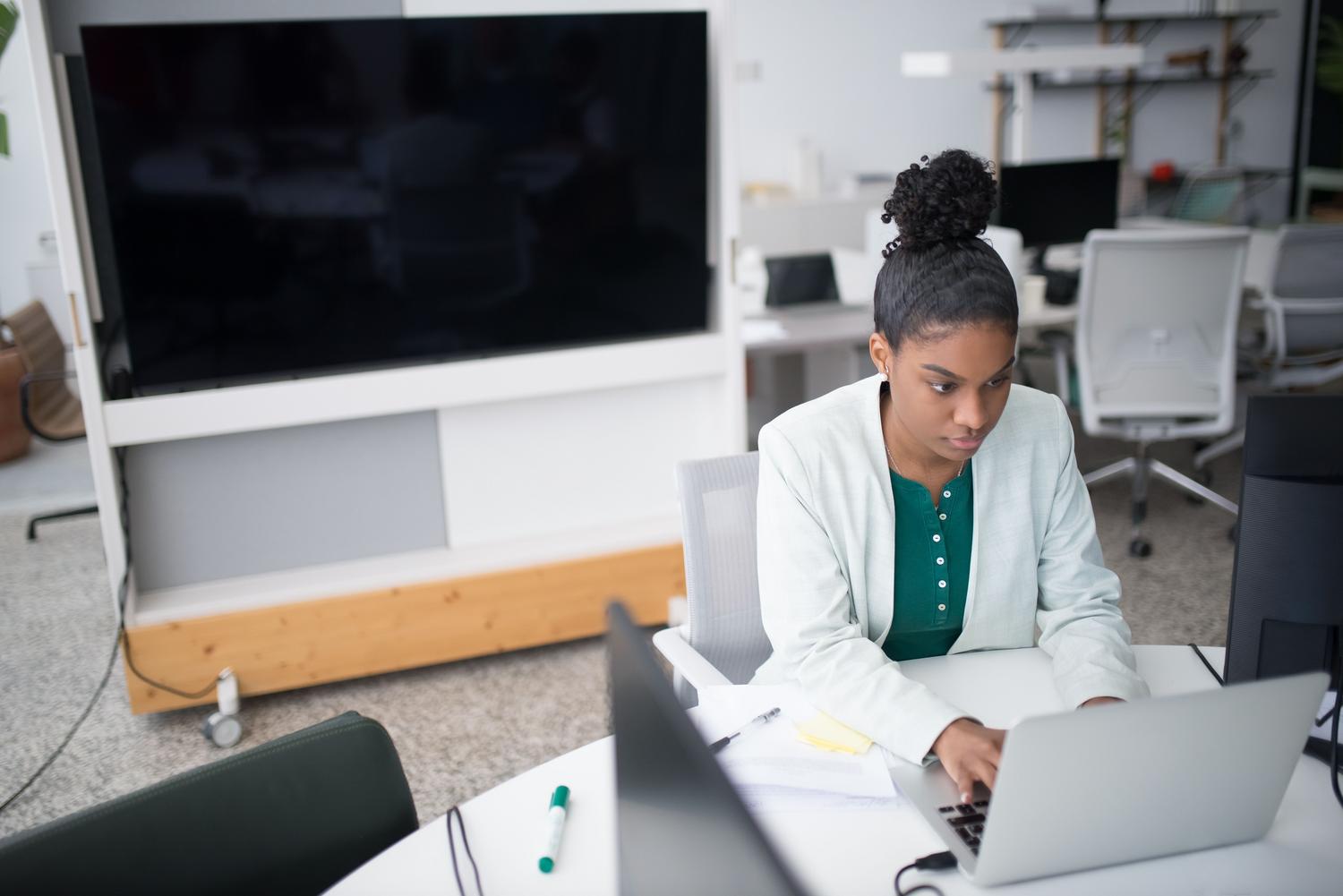 Mujer profesional trabajando en un portátil en una oficina moderna, representando la gestión y recuperación de archivos.