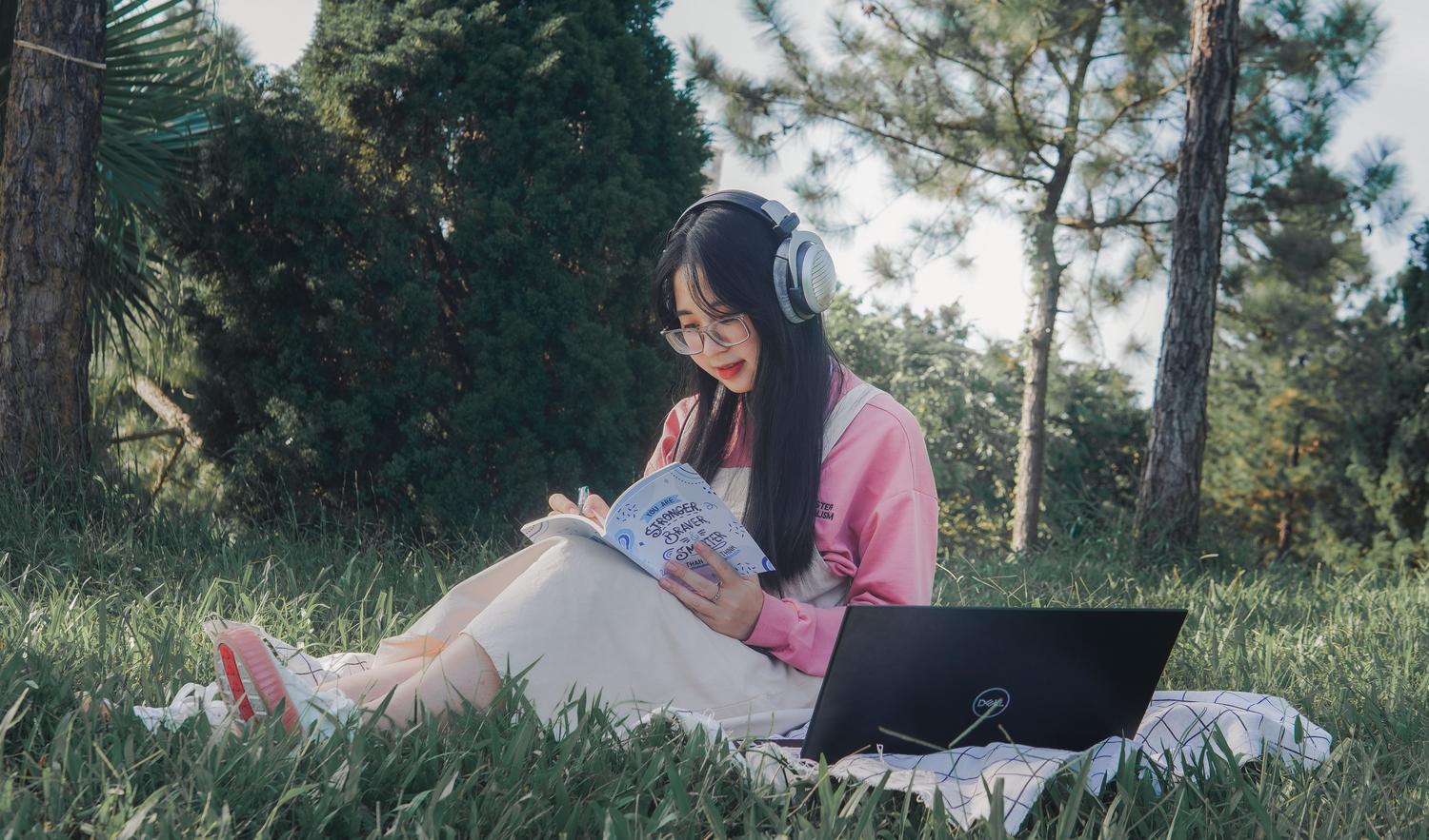 Estudiante utilizando auriculares y portátil al aire libre, representando la función de Resumen de Audio y aprendizaje activo de NotebookLM