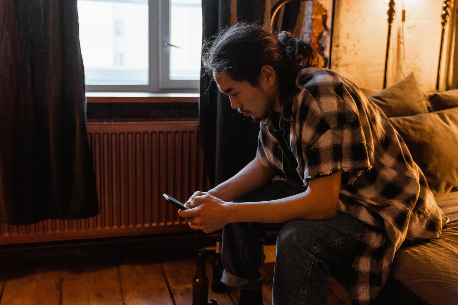 Hombre usando su teléfono móvil en un entorno doméstico acogedor.