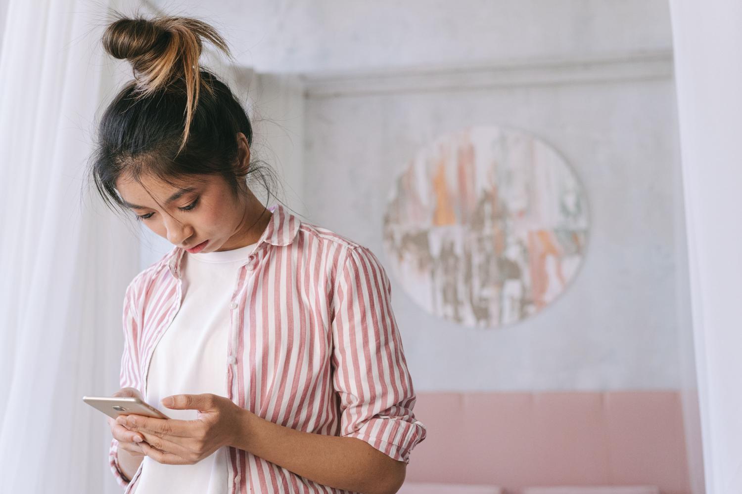 Mujer utilizando un smartphone en casa, representando la configuración de aplicaciones en un entorno cotidiano.
