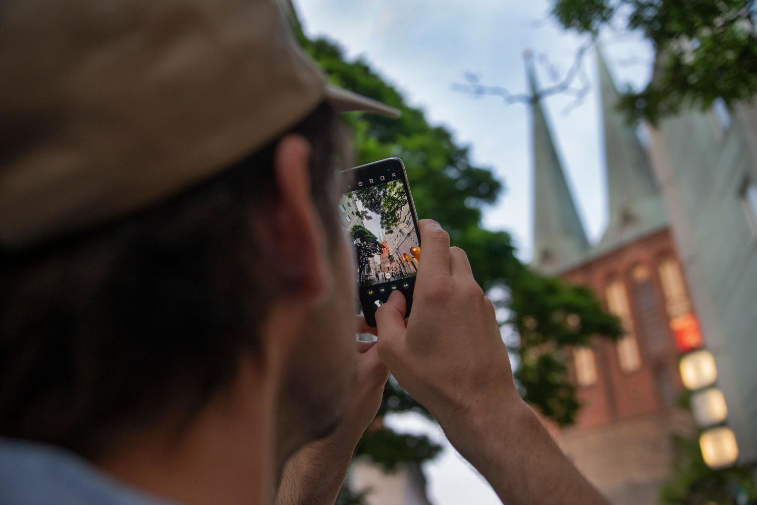 Persona capturando una foto de una torre emblemática con su móvil para añadir a sus recuerdos de viaje