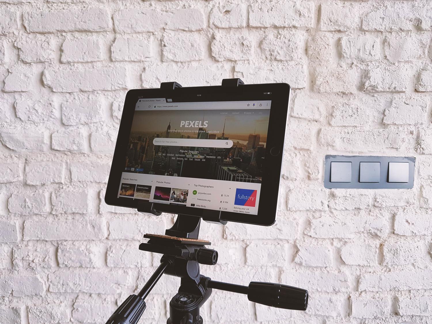 Tablet instalada en un soporte frente a una pared de ladrillo blanco, ilustrando el montaje físico del panel
