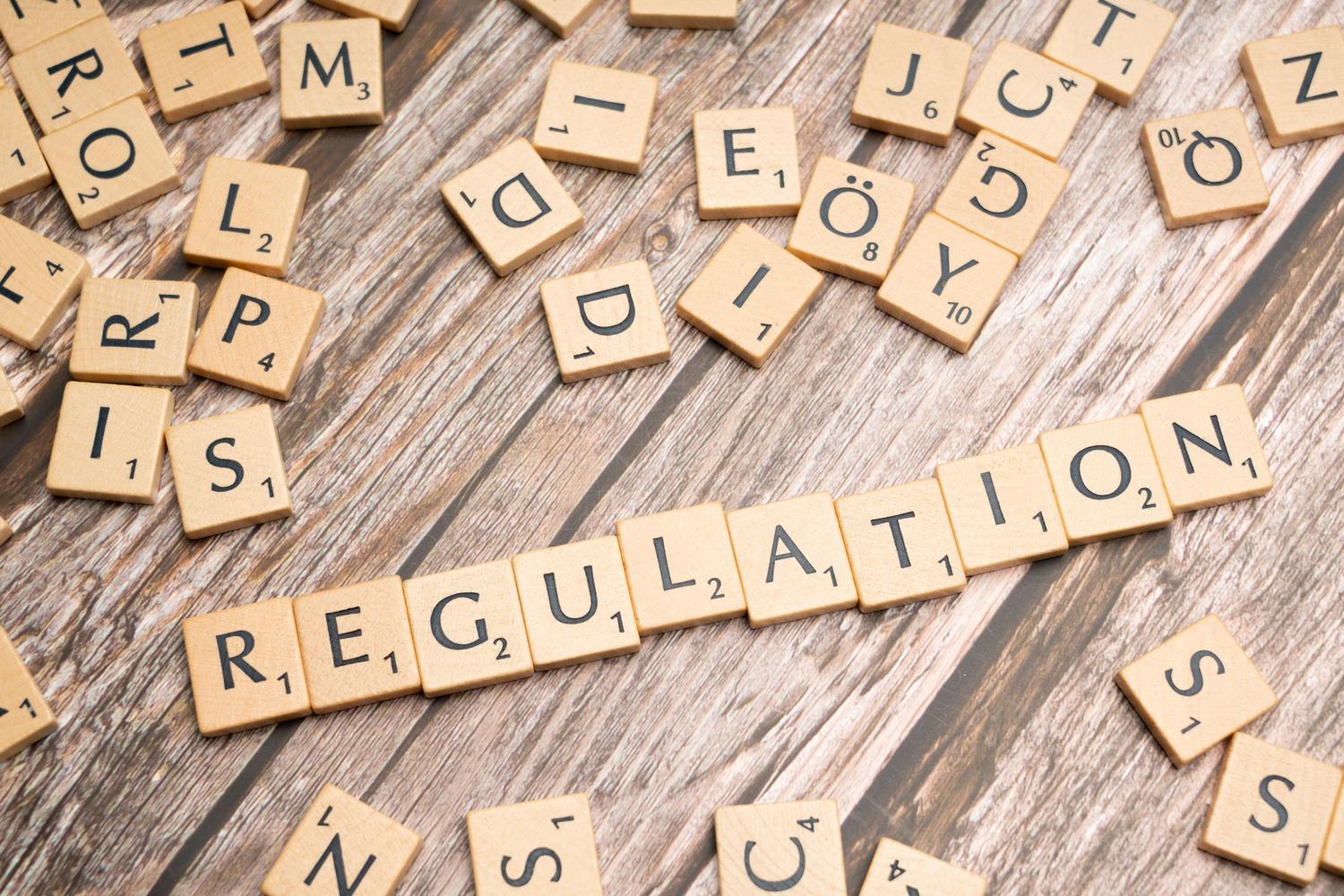Letras de madera formando la palabra 'Regulation', representando la base regulatoria del RegTech. Letras de madera formando la palabra 'Regulation', representando la base regulatoria del RegTech.