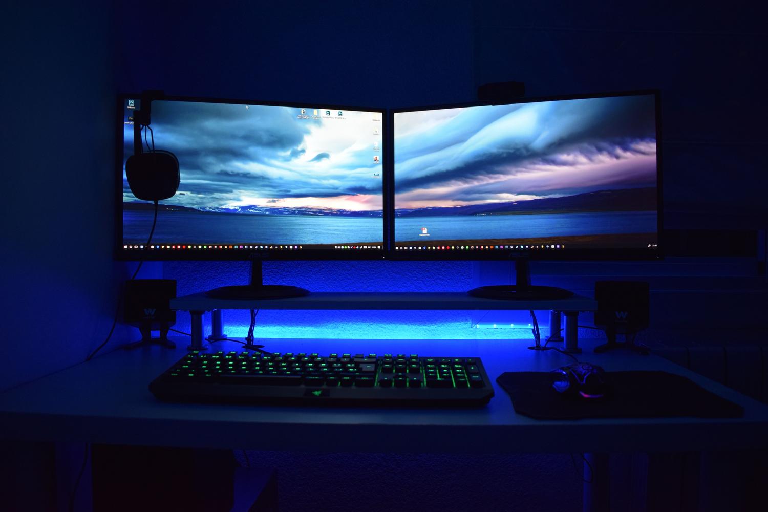 Monitores duales con iluminación LED azul en un entorno de gaming