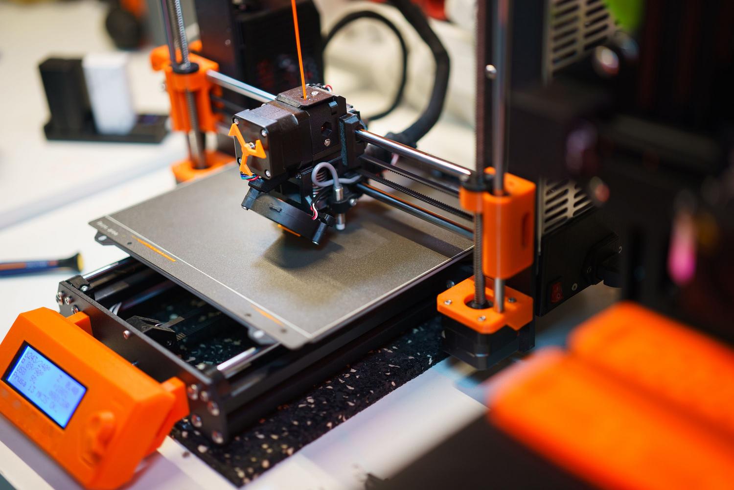 Primer plano de una impresora 3D FDM en pleno proceso de fabricación de una pieza plástica.