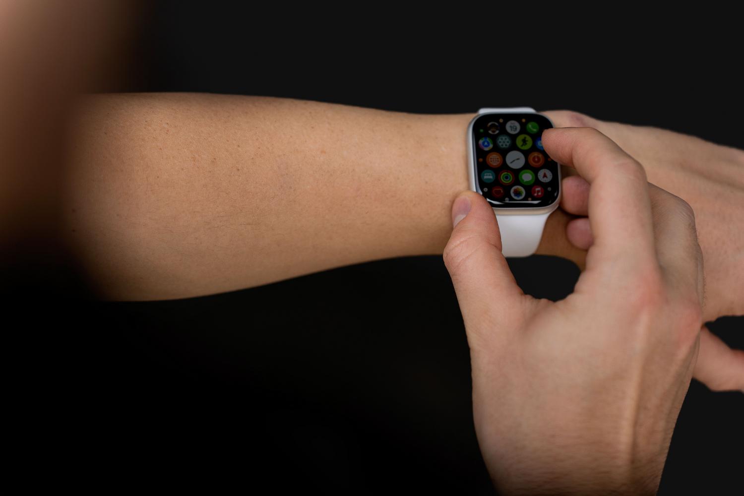 Persona interactuando con la pantalla táctil de un reloj inteligente moderno y funcional sobre un fondo oscuro. Persona interactuando con la pantalla táctil de un reloj inteligente moderno y funcional sobre un fondo oscuro.