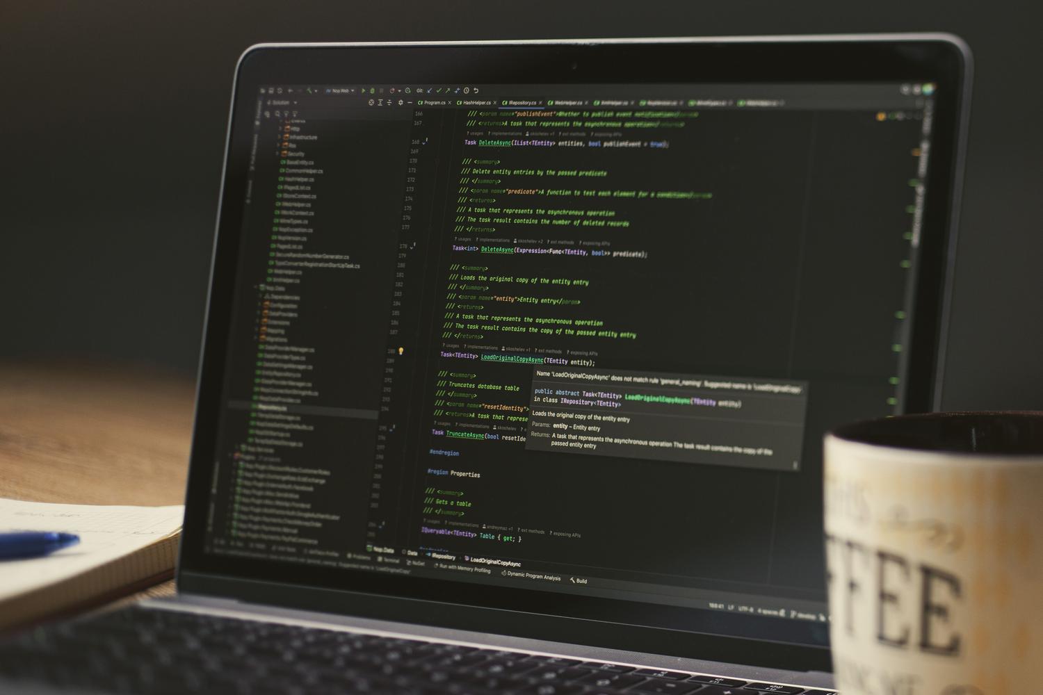 Laptop mostrando líneas de código en un entorno acogedor con una taza de café, representando la fase de instalación técnica mediante Docker Compose