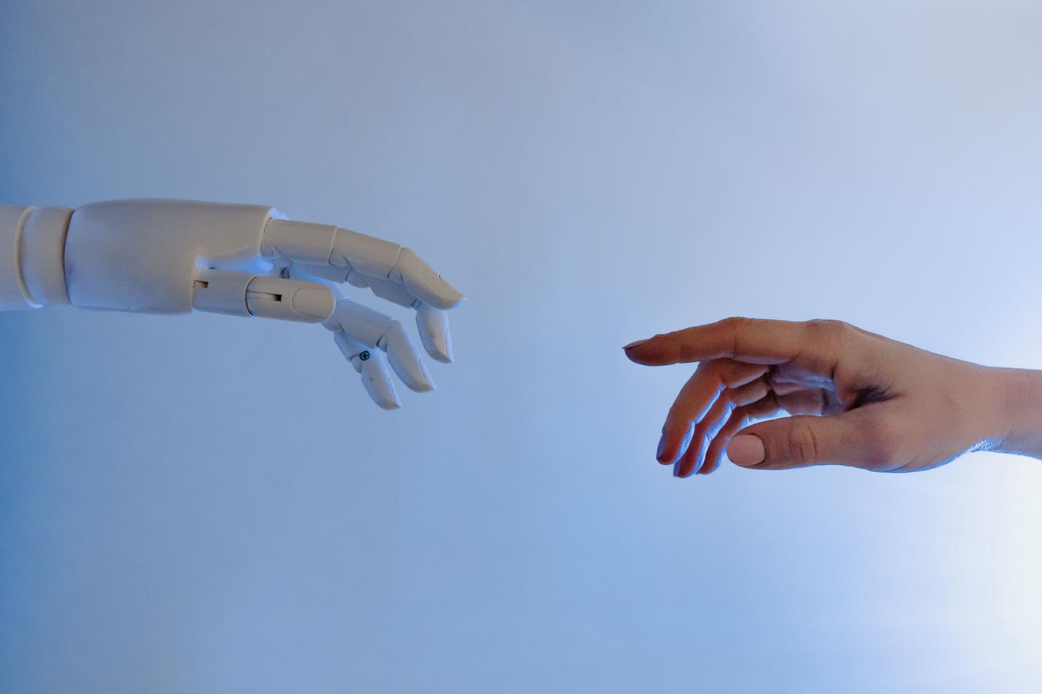 Una mano humana y una mano robótica acercándose, representando el equilibrio entre la tecnología y la supervisión humana real.