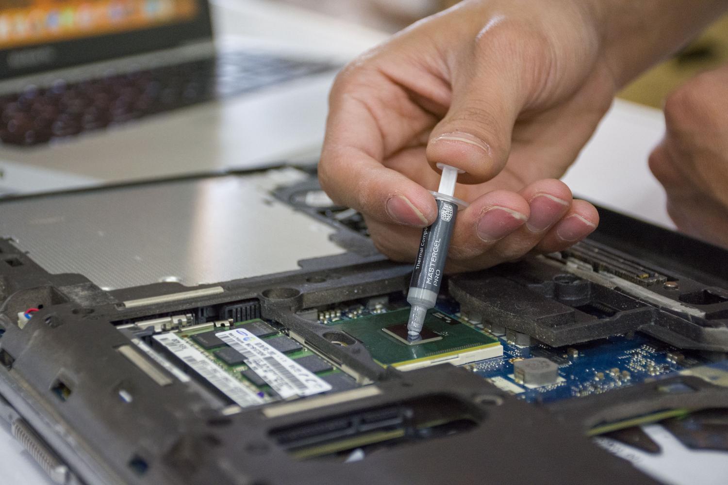 Detalle de una mano aplicando pasta térmica a un microchip de ordenador para su mantenimiento