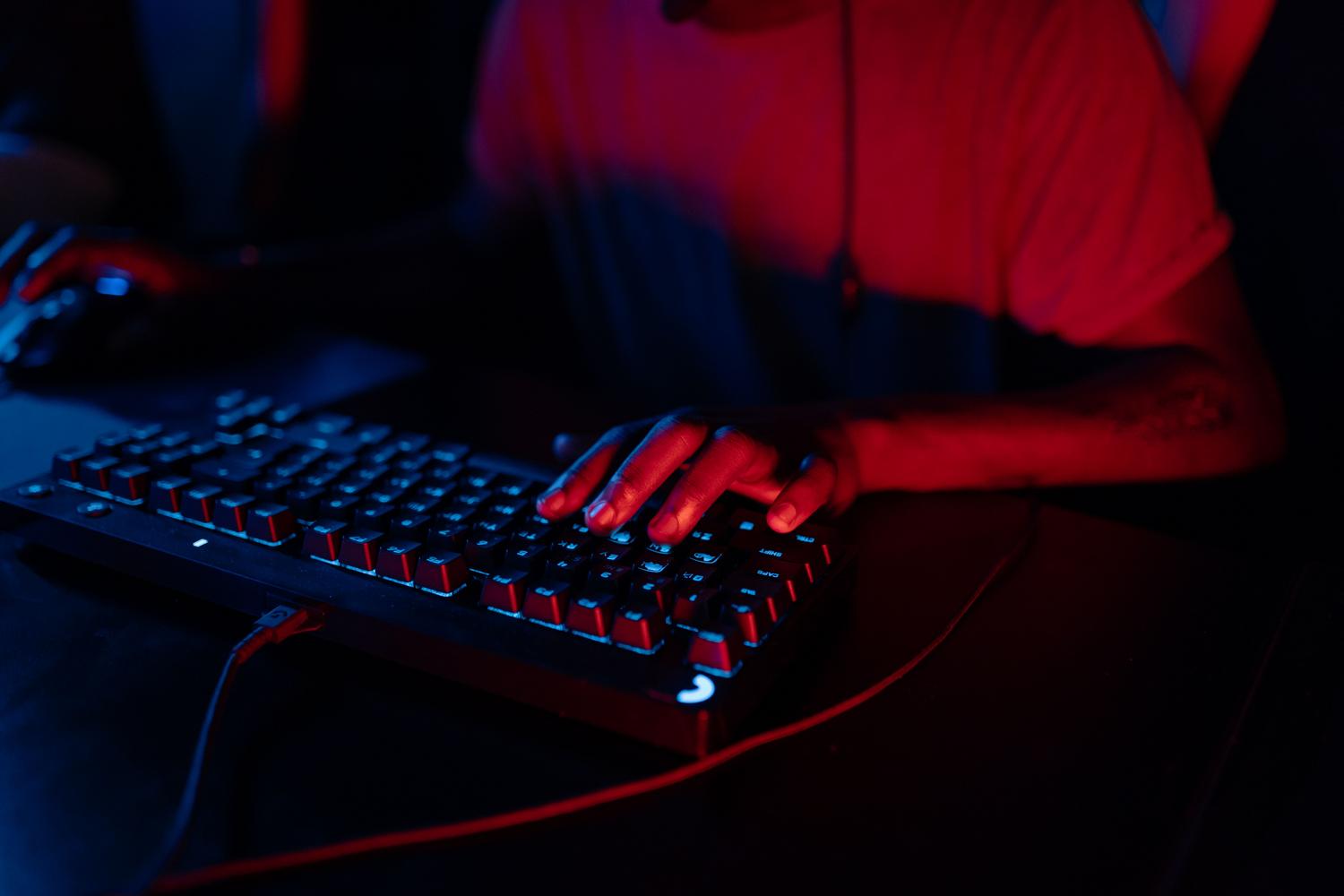 Close-up of hands using an RGB gaming keyboard, symbolizing the technical configuration and optimization of the emulator.