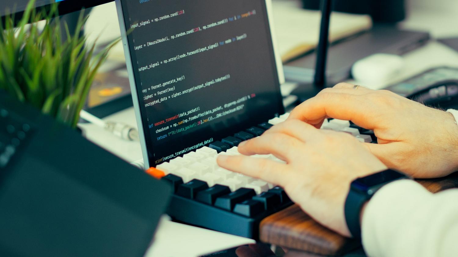 Desarrollador escribiendo código en un teclado con la pantalla mostrando scripts, perfecto para la sección de instalación de Docker.
