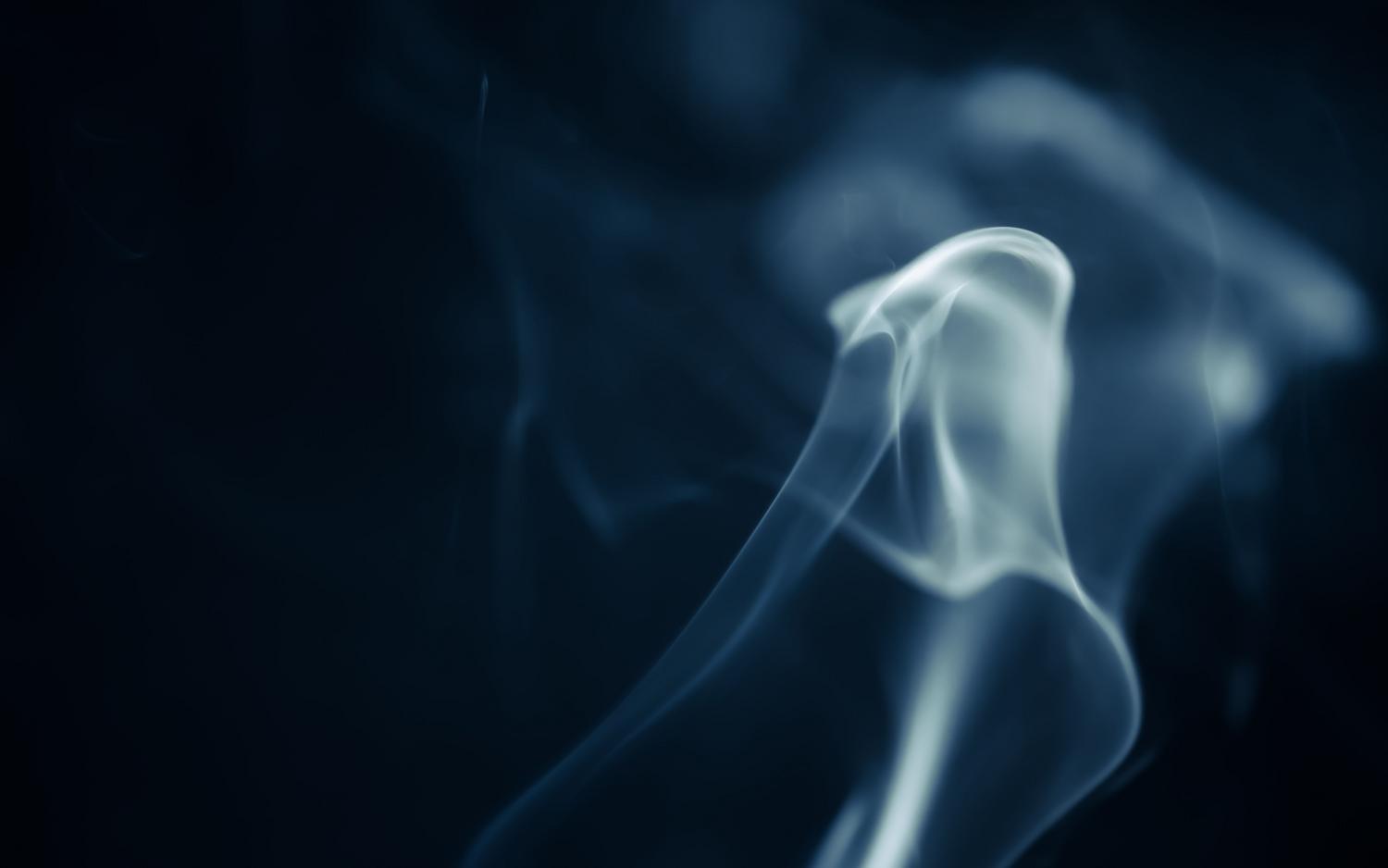 Humo blanco girando en primer plano sobre un fondo oscuro, ejemplificando el movimiento caótico y fluido del aire.
