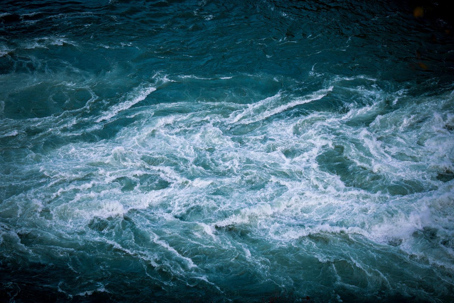 Un remolino dinámico en aguas turquesas que ilustra visualmente la turbulencia y la dinámica de fluidos.