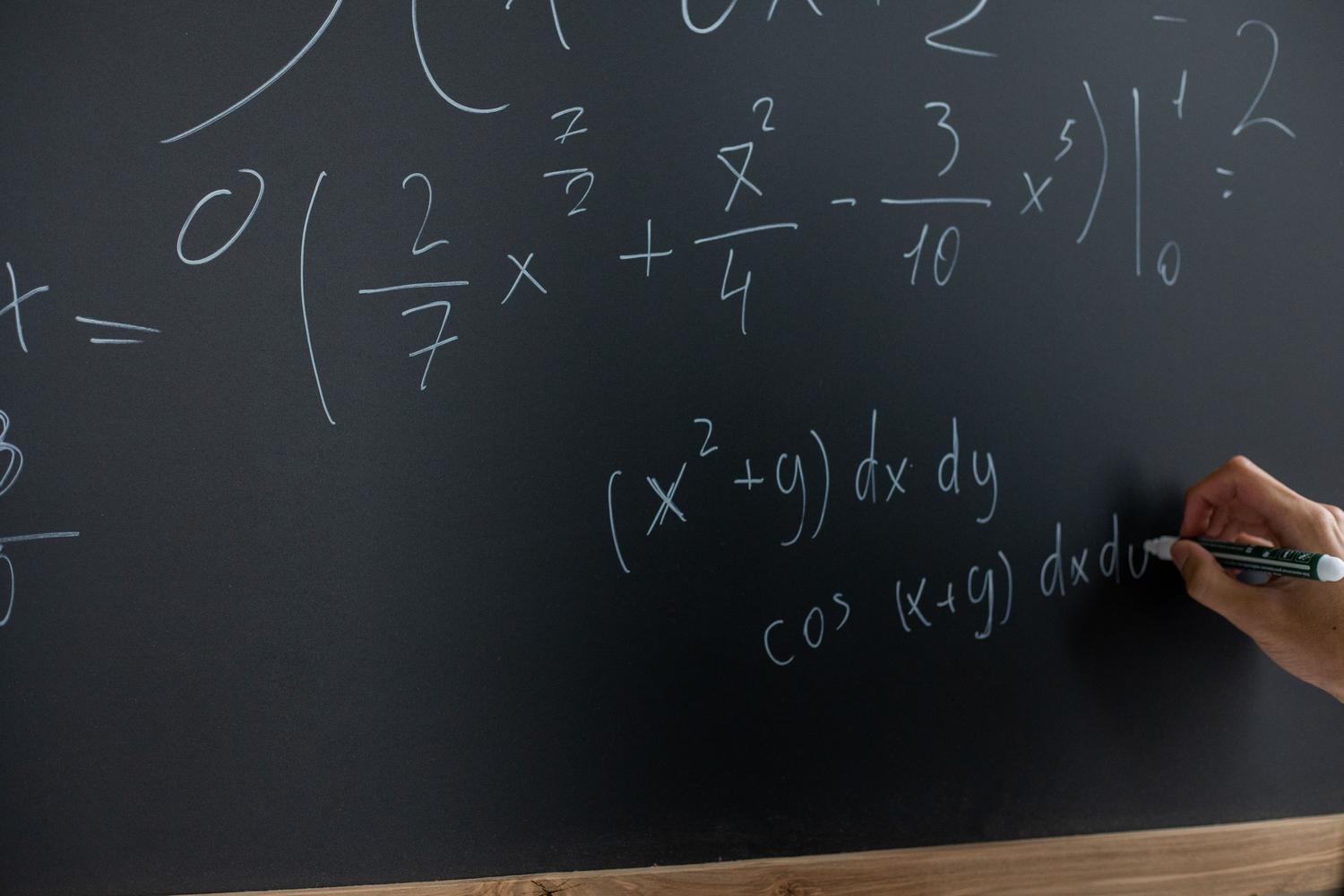 Mano escribiendo ecuaciones matemáticas en una pizarra, simbolizando la búsqueda de una demostración rigurosa para resolver el problema del milenio.