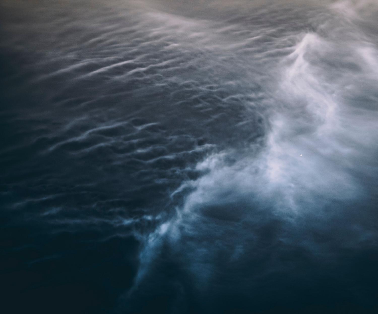 Toma aérea de olas oceánicas tormentosas creando patrones dinámicos, reflejando la complejidad física de las ecuaciones de Navier-Stokes.
