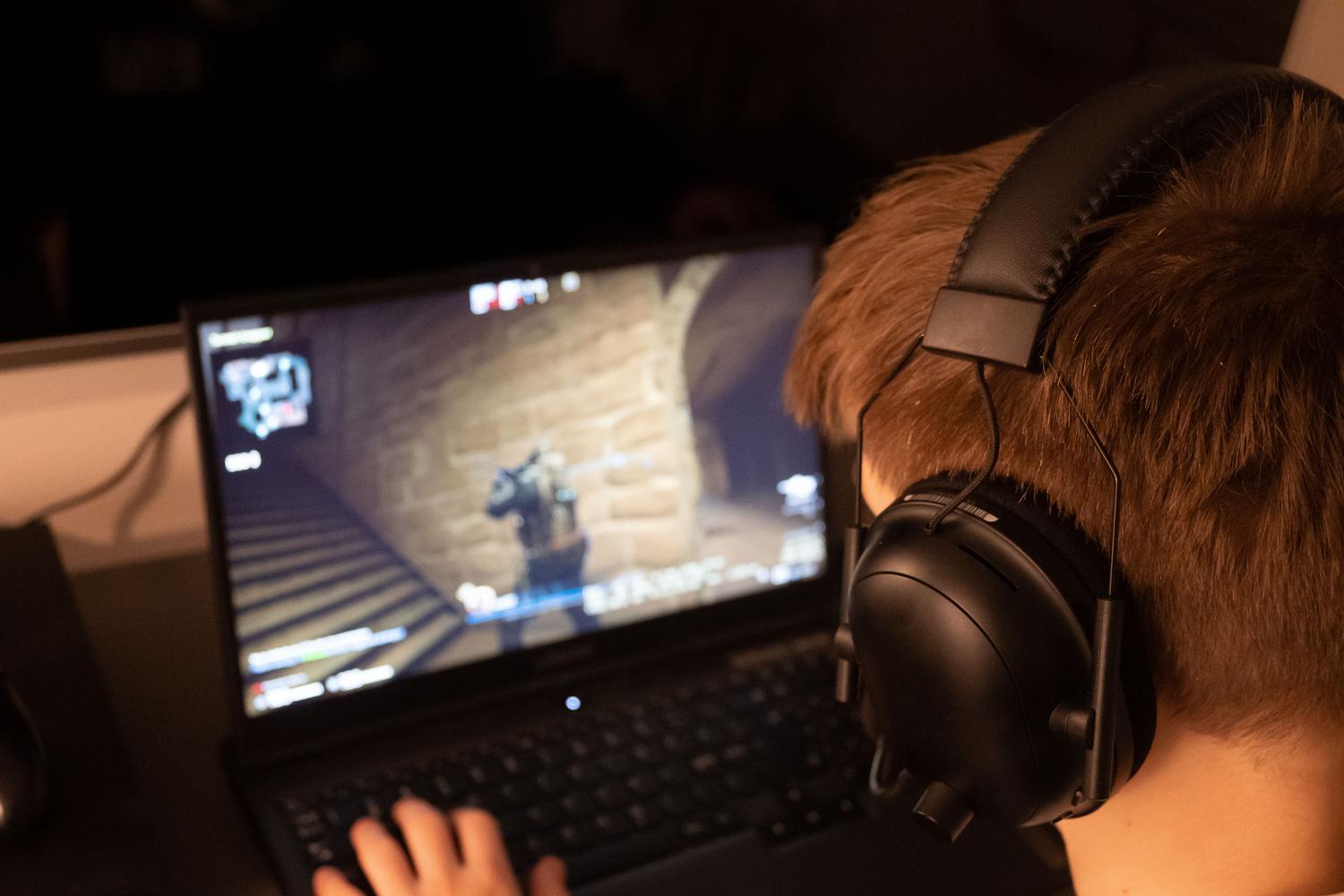 Joven concentrado jugando a un videojuego en la pantalla de un ordenador portátil, ideal para ilustrar la sección de juegos competitivos.