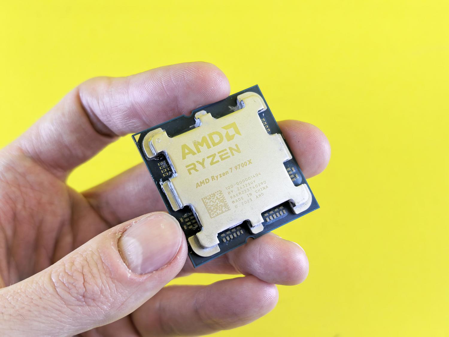 Primer plano de un procesador AMD Ryzen 7 9700X sostenido en la mano, destacando la marca y el modelo.