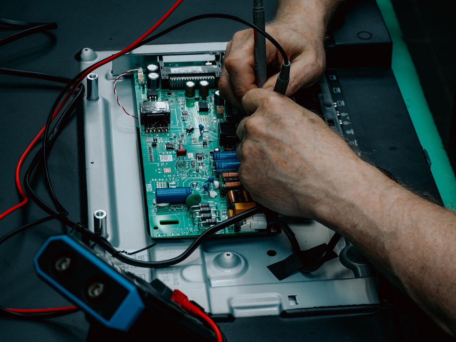 Técnico especializado reparando una placa de circuito electrónico de un dispositivo.