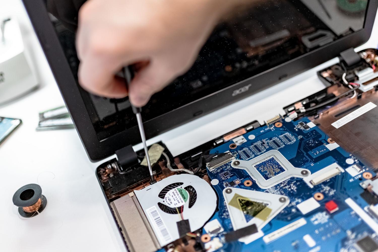 Técnico profesional manipulando la placa base y componentes internos de un portátil para realizar un mantenimiento especializado. Técnico profesional manipulando la placa base y componentes internos de un portátil para realizar un mantenimiento especializado.