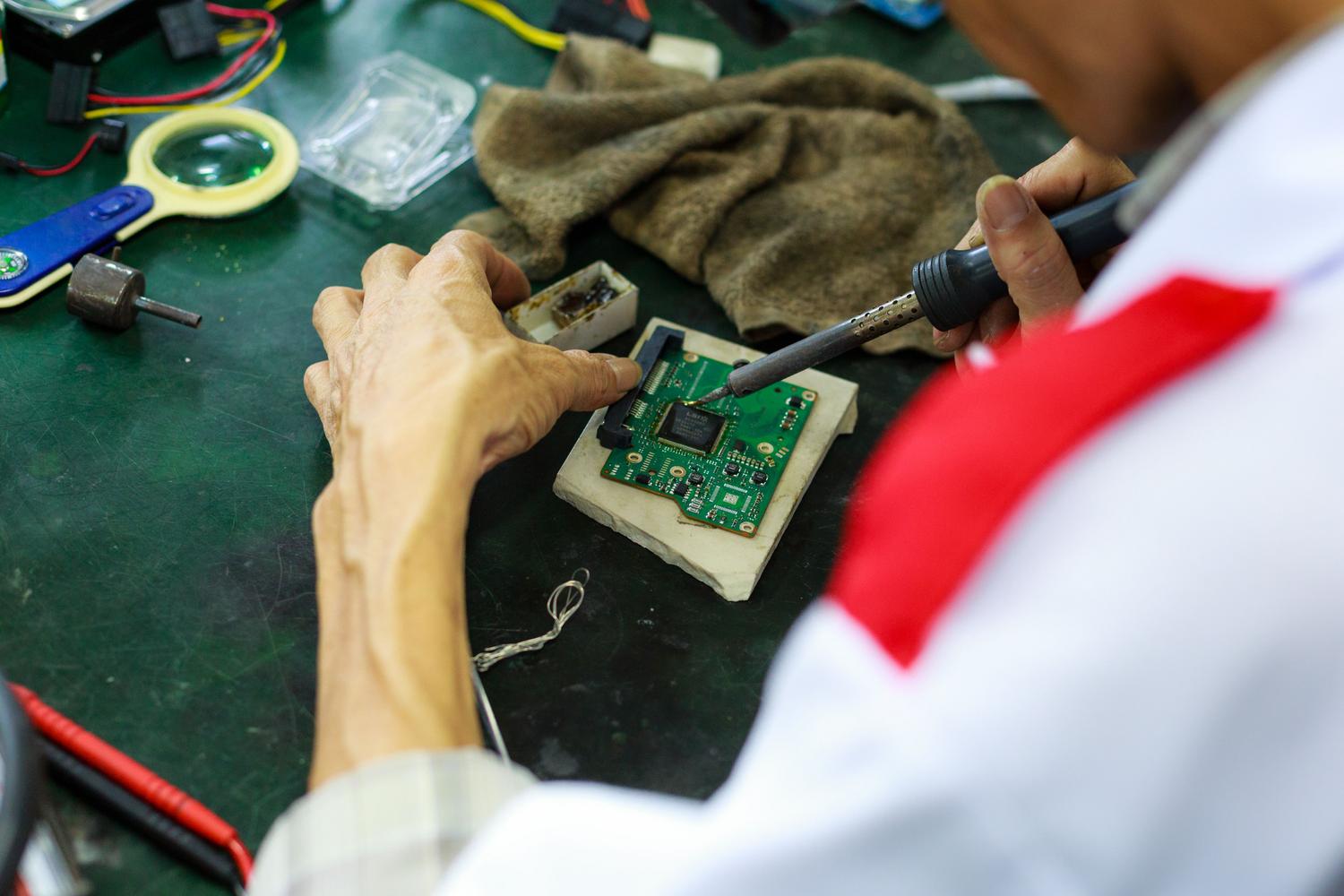 Técnico utilizando un soldador para sustituir componentes dañados en una placa de circuito impreso. Técnico utilizando un soldador para sustituir componentes dañados en una placa de circuito impreso.