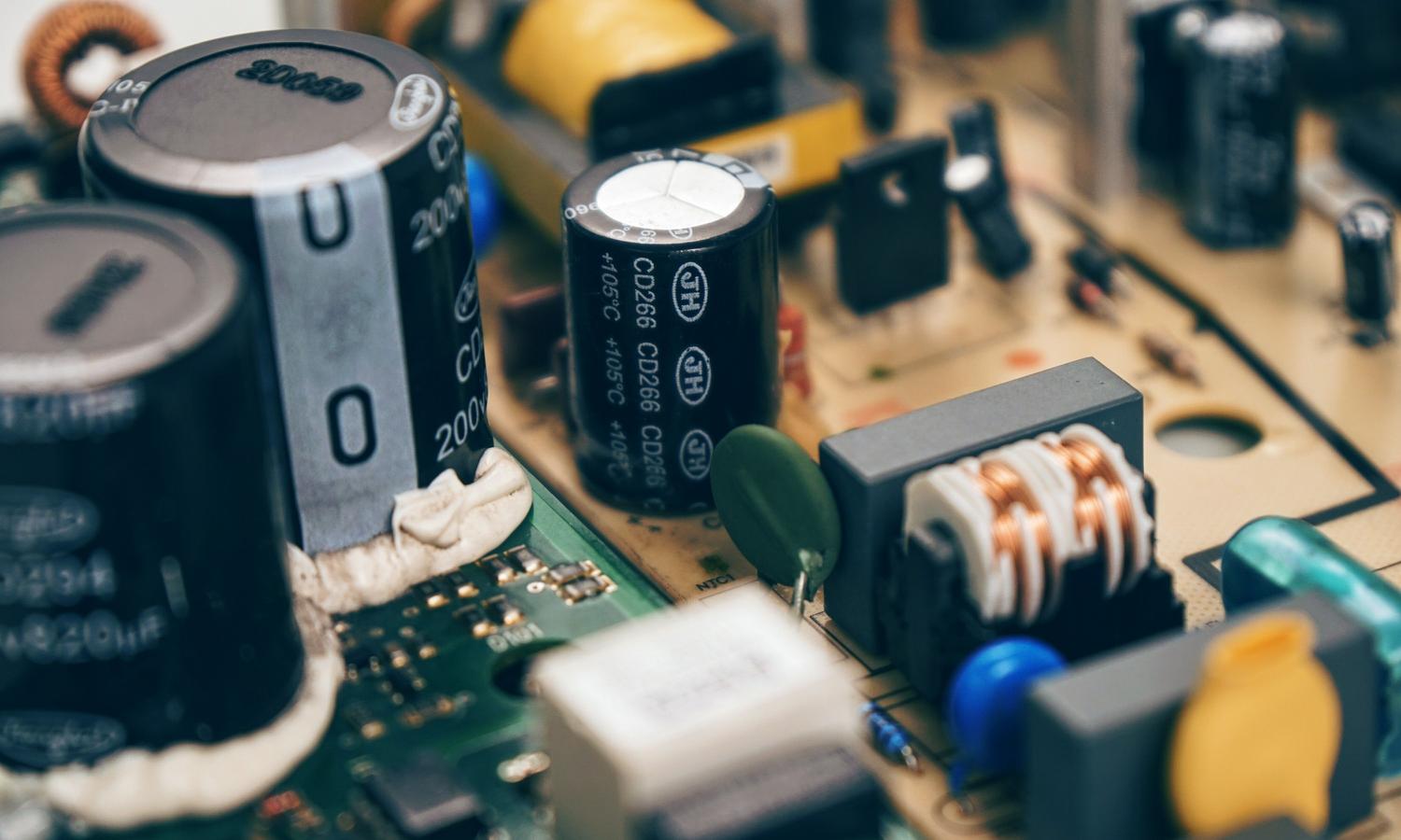 Primer plano detallado de condensadores electrolíticos y otros componentes en una placa de circuito electrónico. Primer plano detallado de condensadores electrolíticos y otros componentes en una placa de circuito electrónico.