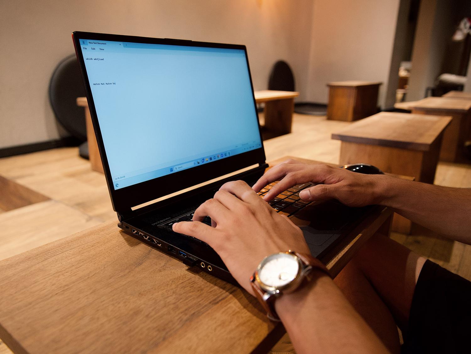 Une personne travaillant à distance avec un ordinateur portable dans un environnement moderne, ce qui souligne l'importance d'une connexion stable dans tout le domicile.