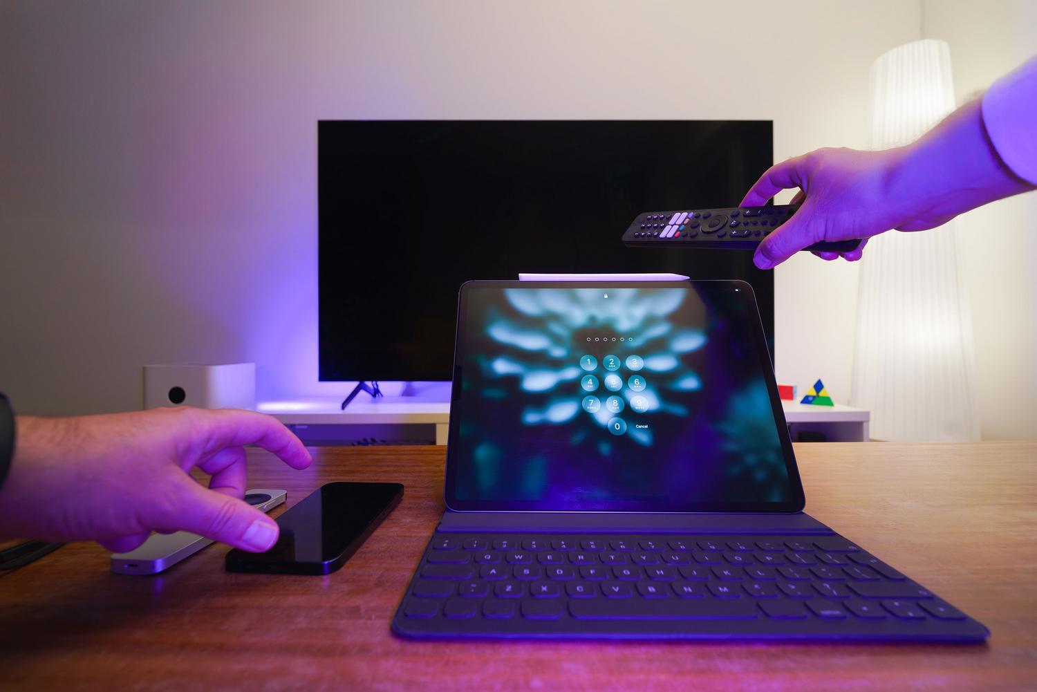 Ecosistema de dispositivos digitales incluyendo Smart TV, tablet y smartphone con iluminación ambiental tecnológica.