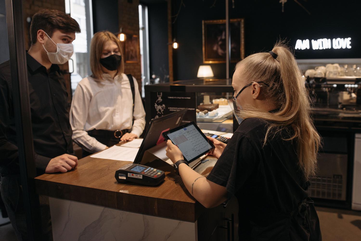Barista gestionando el cobro y el pedido mediante una tablet y un terminal de pago electrónico.