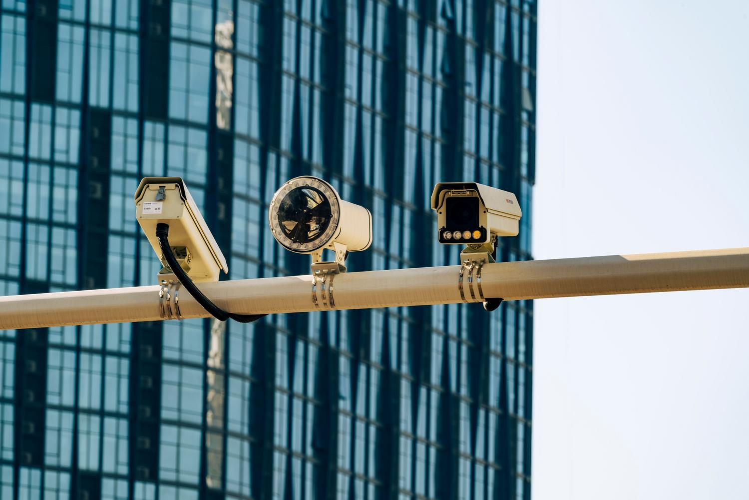 Cámaras de videovigilancia profesionales instaladas frente a un edificio corporativo moderno, representando la seguridad integrada empresarial.