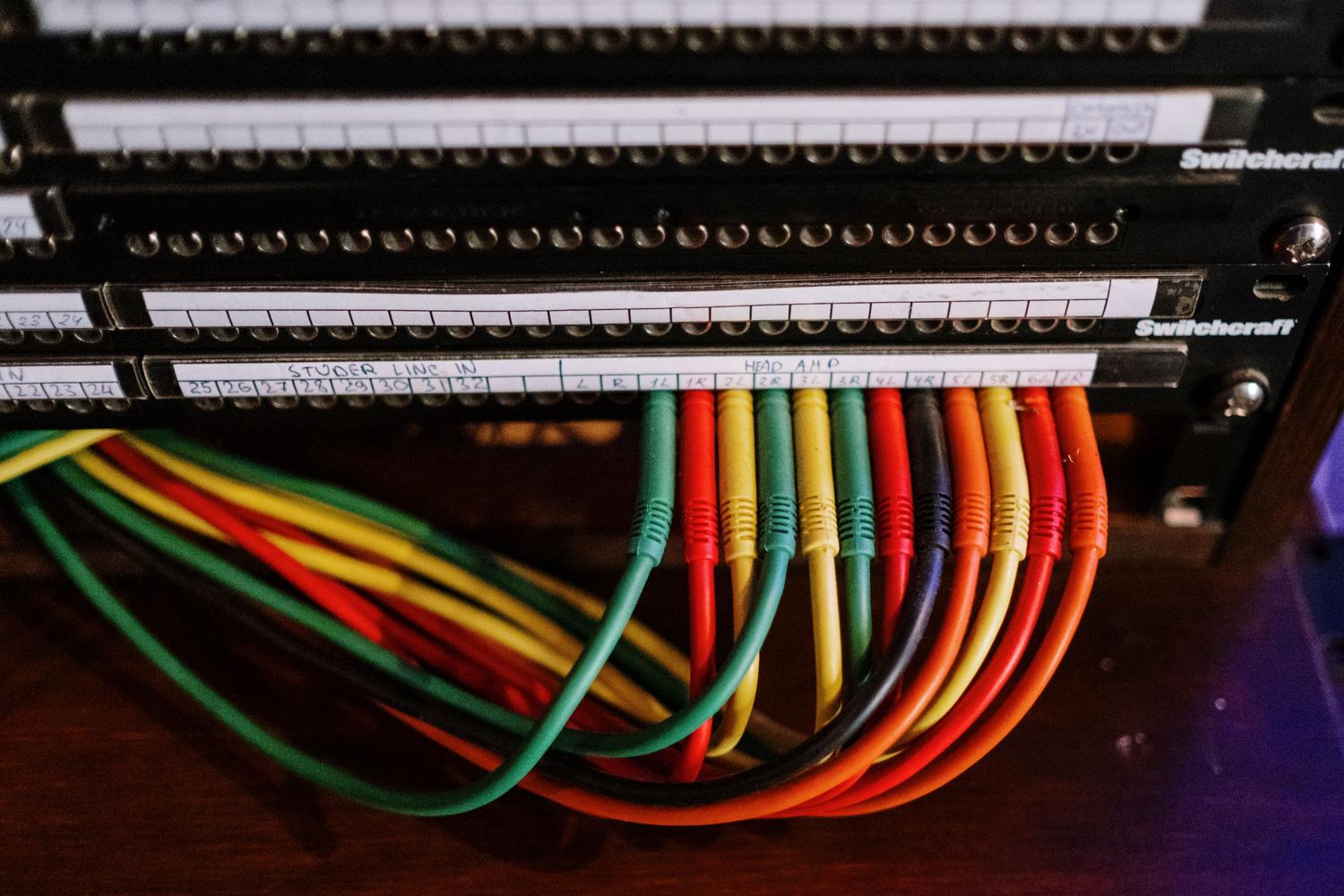 Detalle de cables de red de colores conectados a un panel de parcheo, simbolizando la organización y el flujo de datos en una red local. Detalle de cables de red de colores conectados a un panel de parcheo, simbolizando la organización y el flujo de datos en una red local.