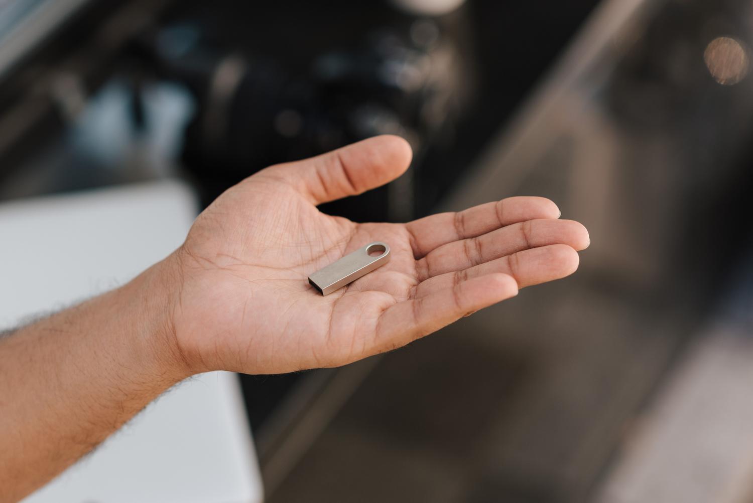 Muž držící v dlani moderní USB flash disk, ideální pro představení konceptu přenosného úložiště.