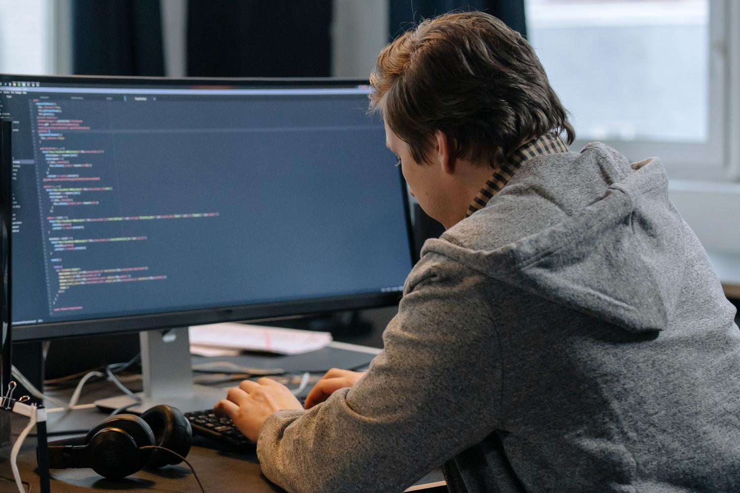 Programador trabajando en un entorno profesional con múltiples monitores y código en pantalla.