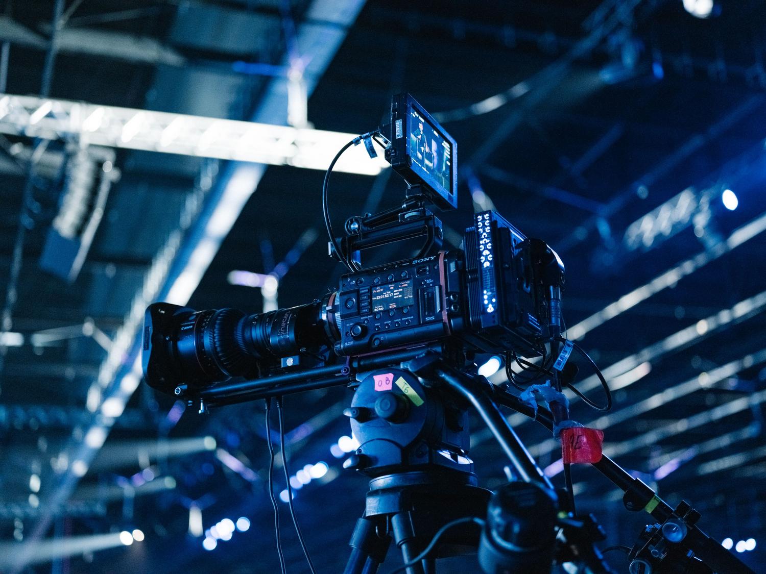 Cámara de vídeo profesional de alta gama montada en trípode, preparada para la captura de contenido en eventos en vivo.