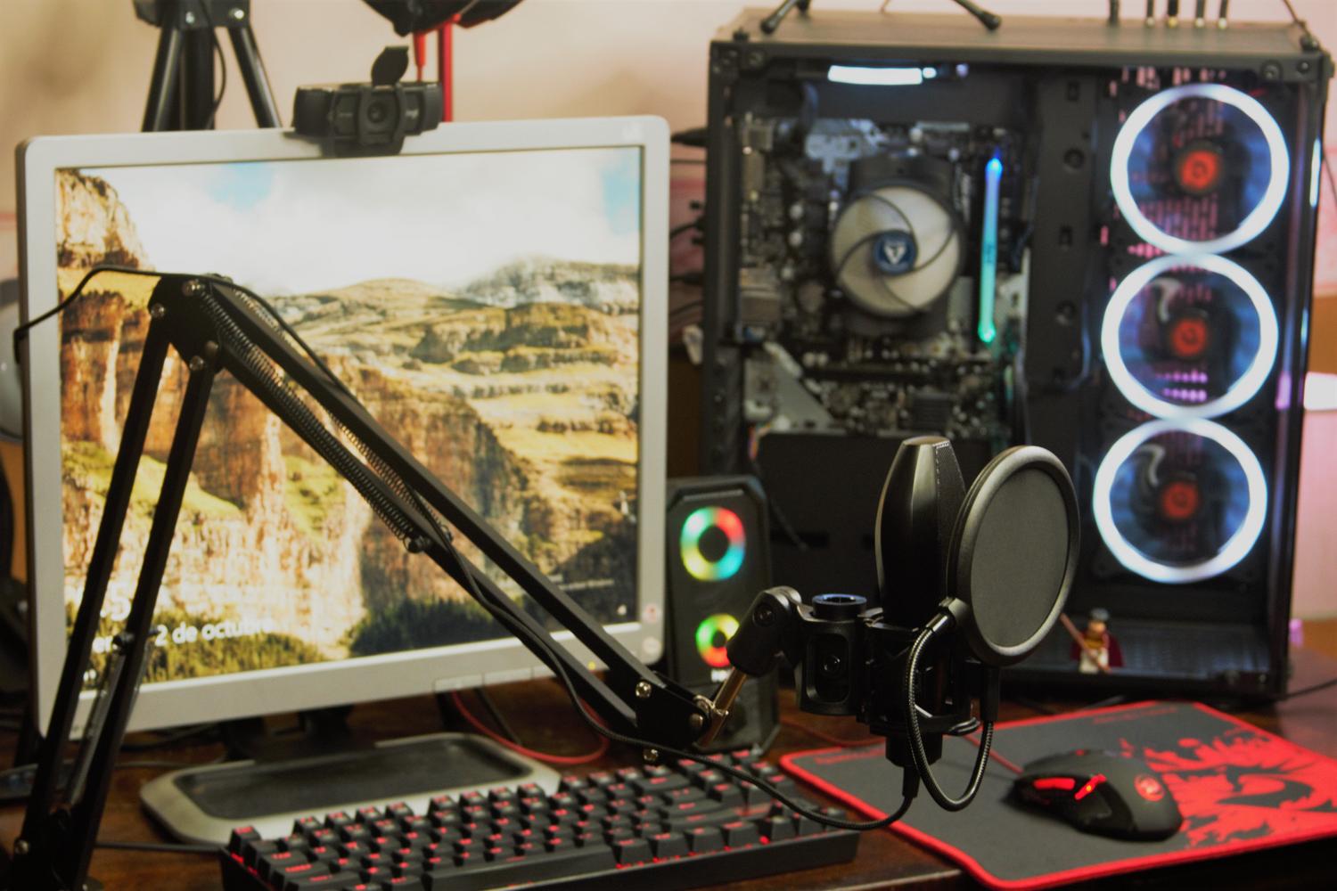 Configuración de PC gaming con micrófono en brazo articulado e iluminación RGB, representando el uso del micrófono para streaming y juegos.