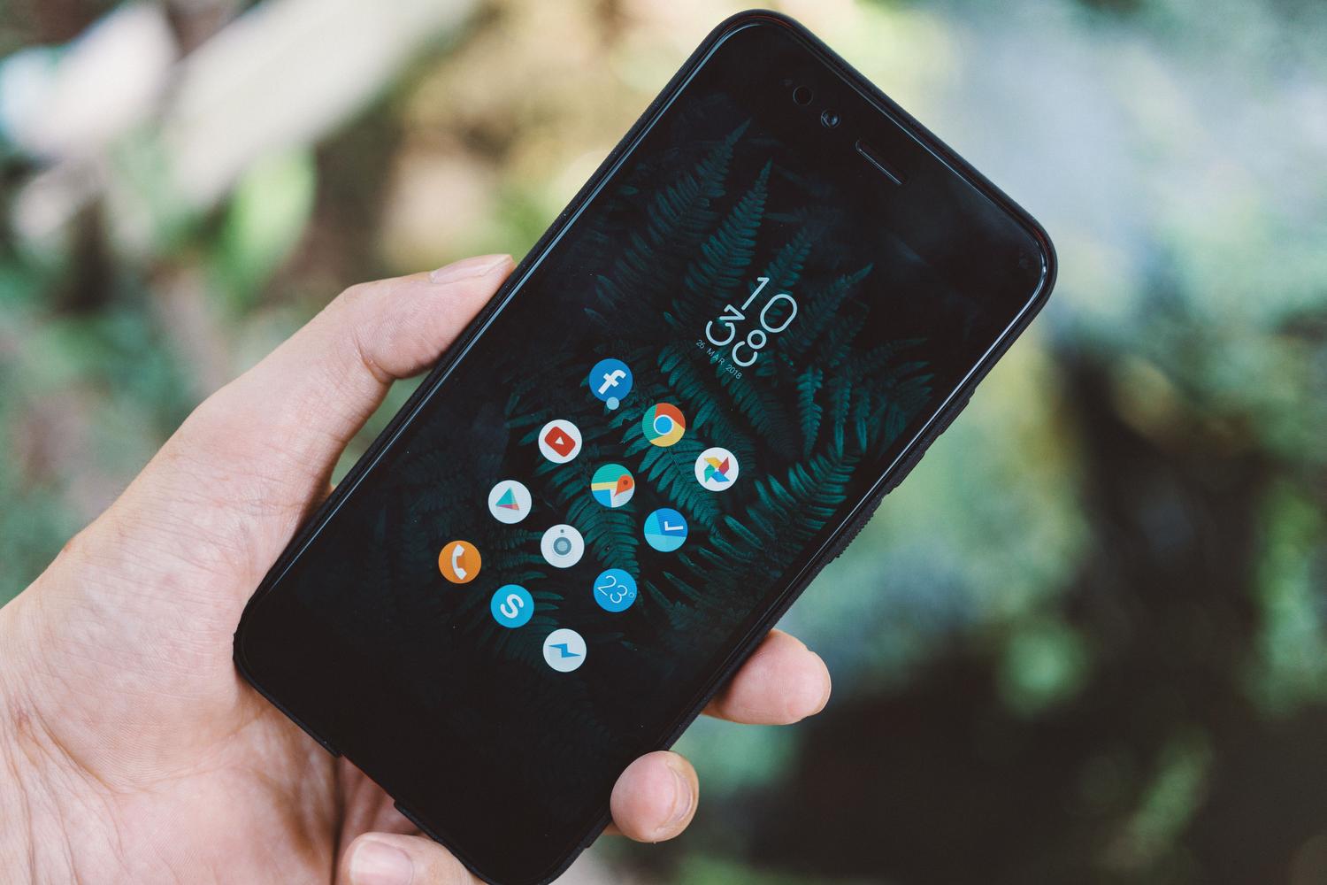 Primer plano de una mano sosteniendo un smartphone Android con iconos de aplicaciones en pantalla.