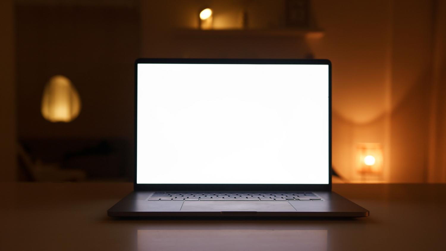 Un ordenador portátil moderno con pantalla en blanco sobre un escritorio de madera, evocando la sensación de un sistema limpio y optimizado.