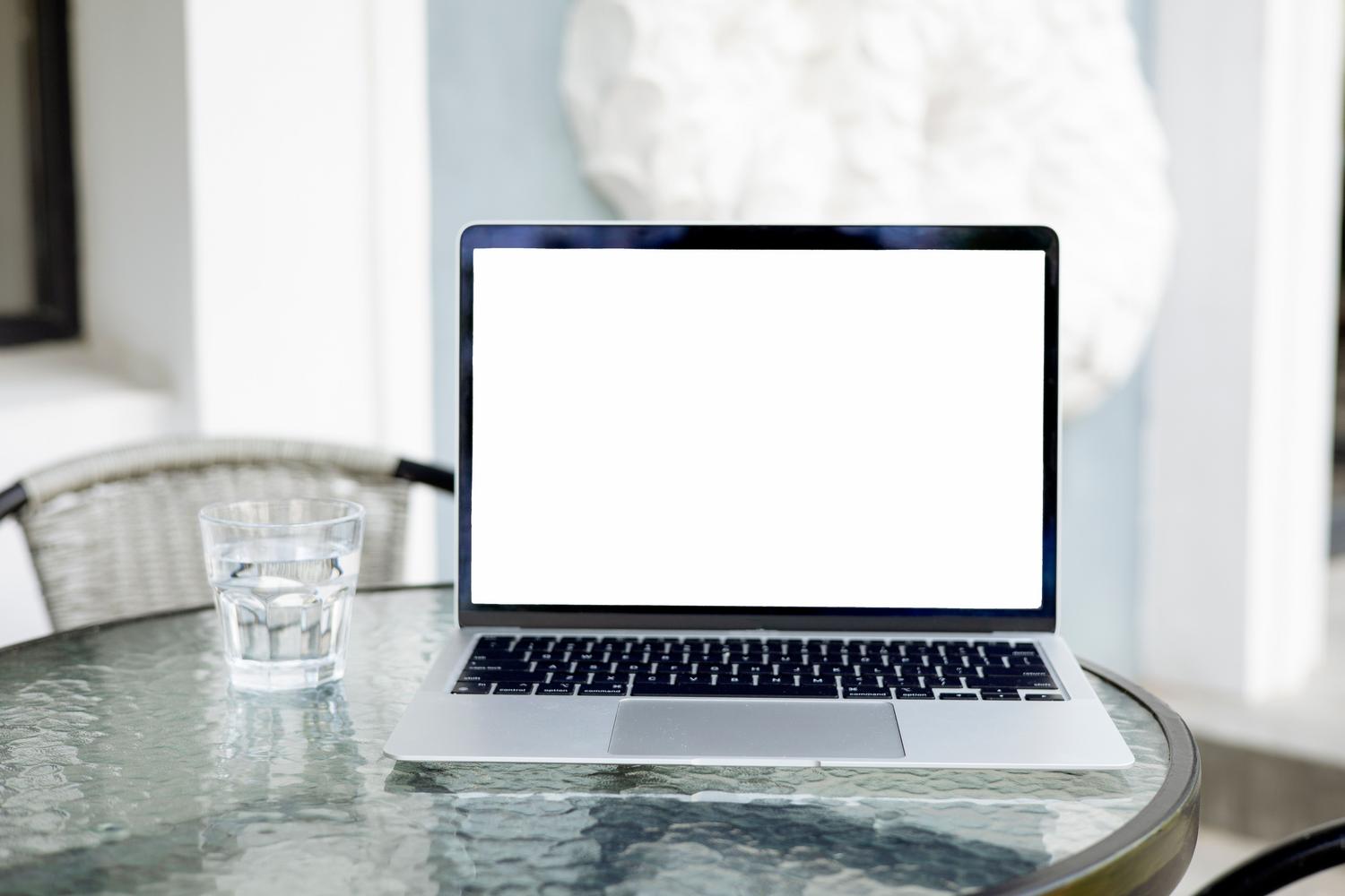 Ordenador portátil con pantalla en blanco sobre una mesa de cristal, imagen genérica para guía de software