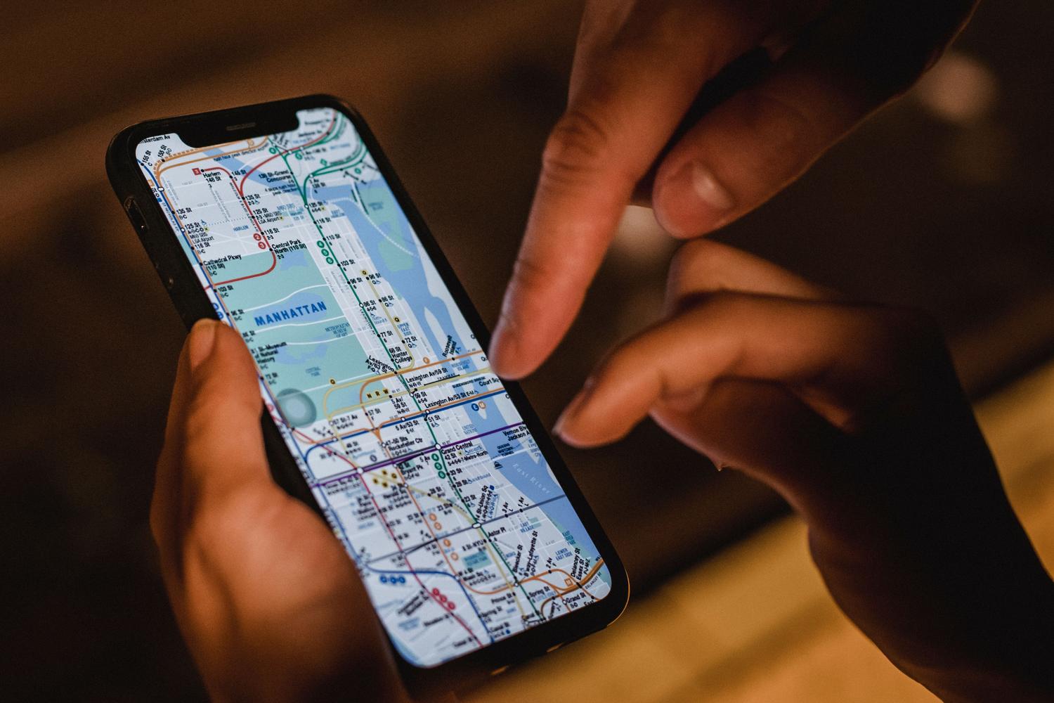 Pareja consultando un mapa digital de la ciudad en la pantalla de un teléfono móvil en un entorno urbano nocturno.