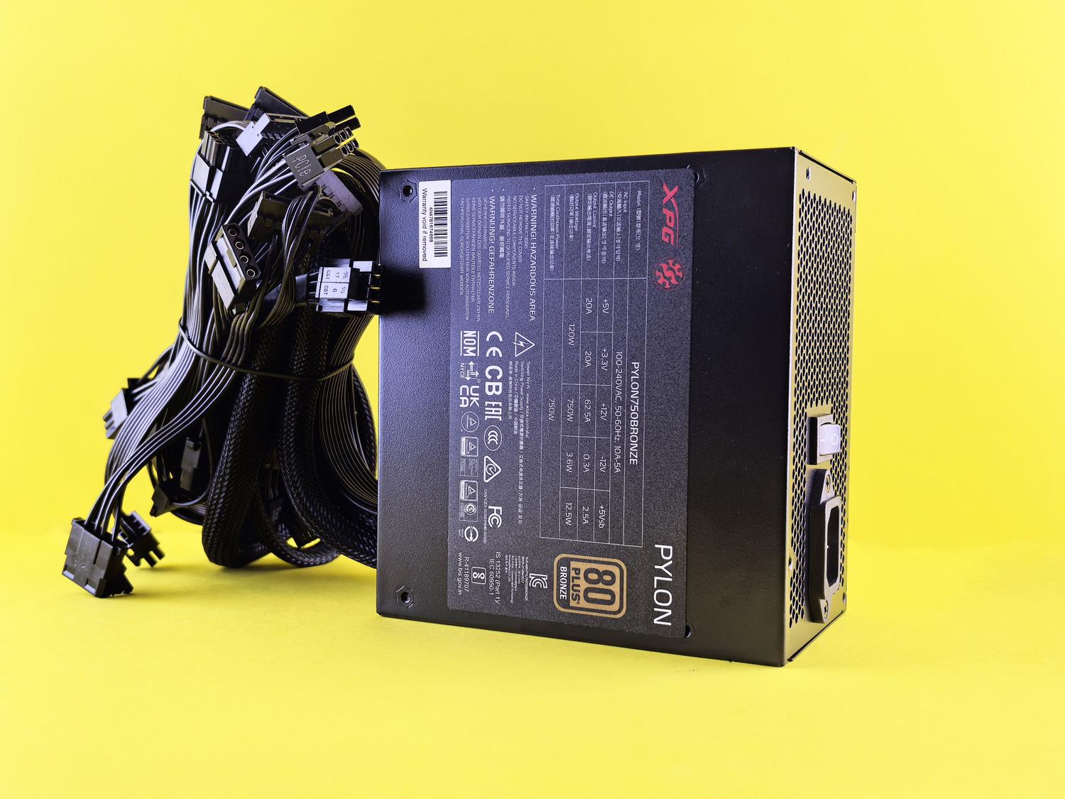 Fuente de alimentación de PC negra con cables sobre fondo amarillo, componente crítico que se recomienda comprar nuevo.